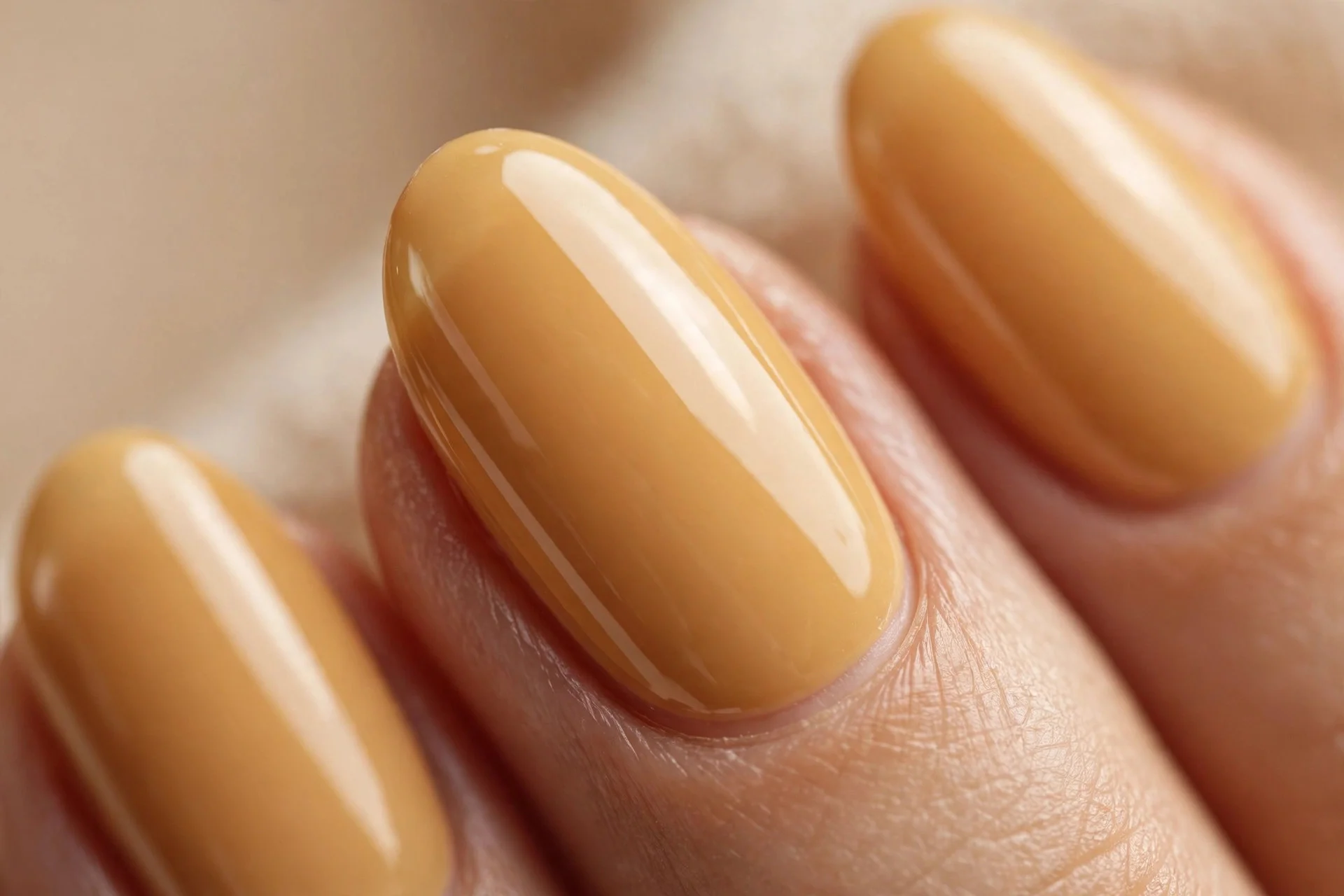 Almond nails in a true honey golden creme polish, glossy, beige background