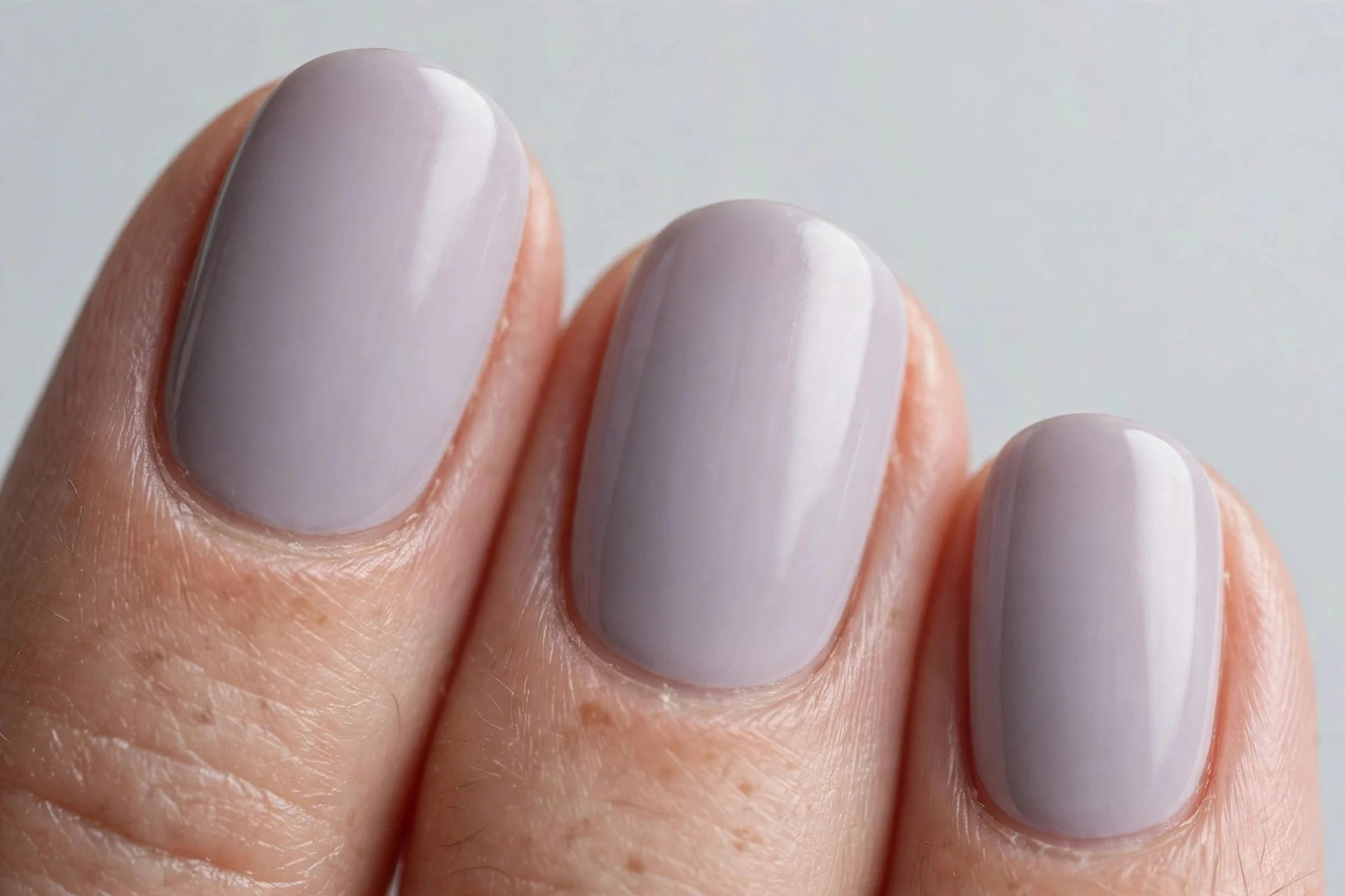 Oval nails in soft grey-lilac crème polish, light grey background