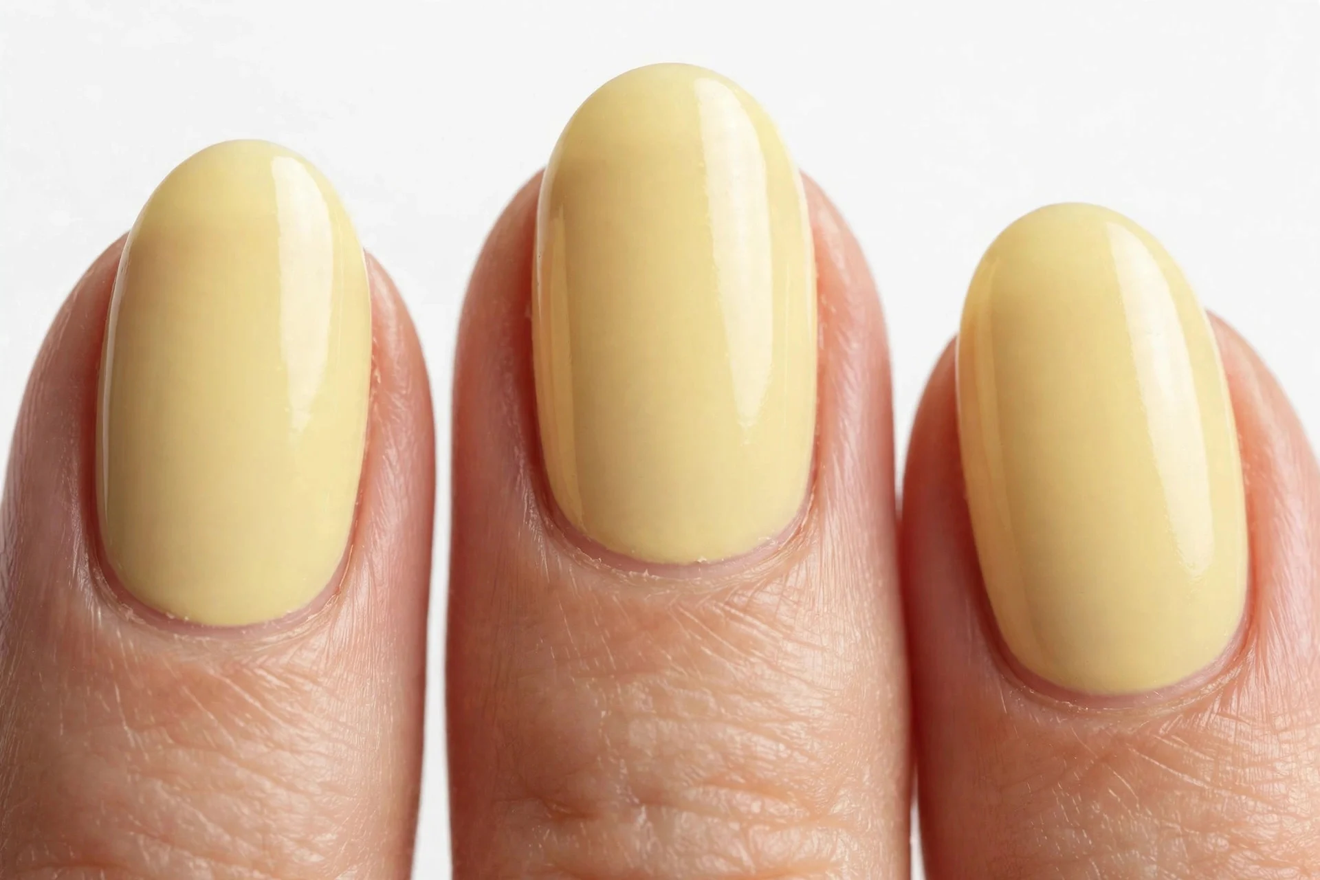 Short almond nails in pale buttery yellow gel, white background