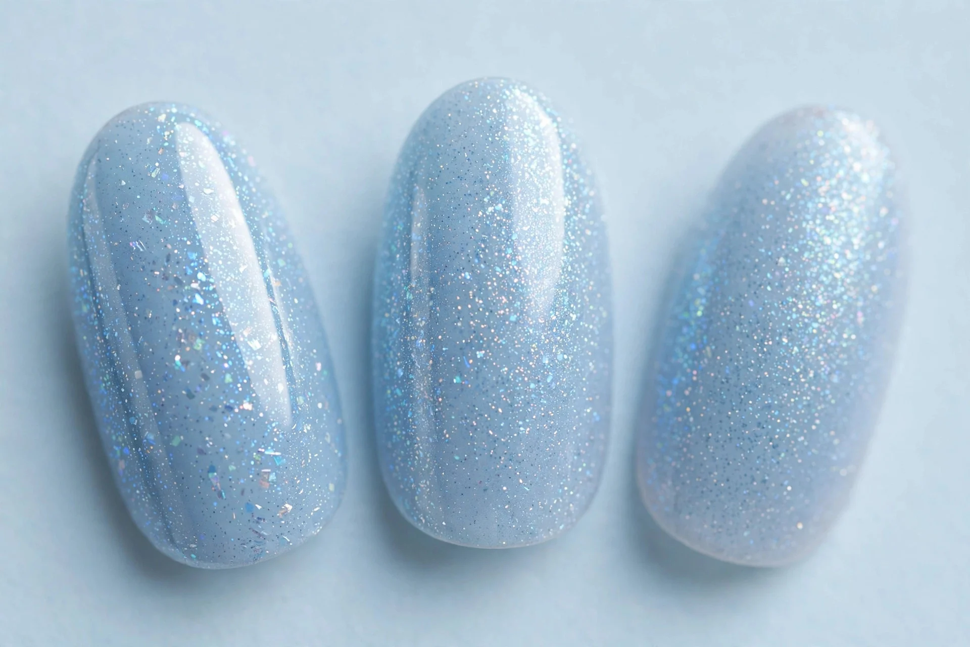 Almond nails in frosty ice blue shimmer gel, pale blue background