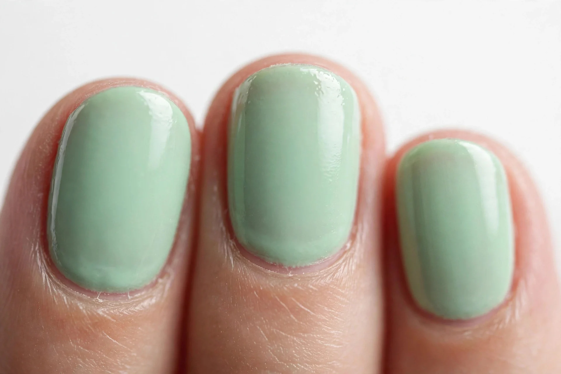 Short oval nails in soft mint green gel, white background
