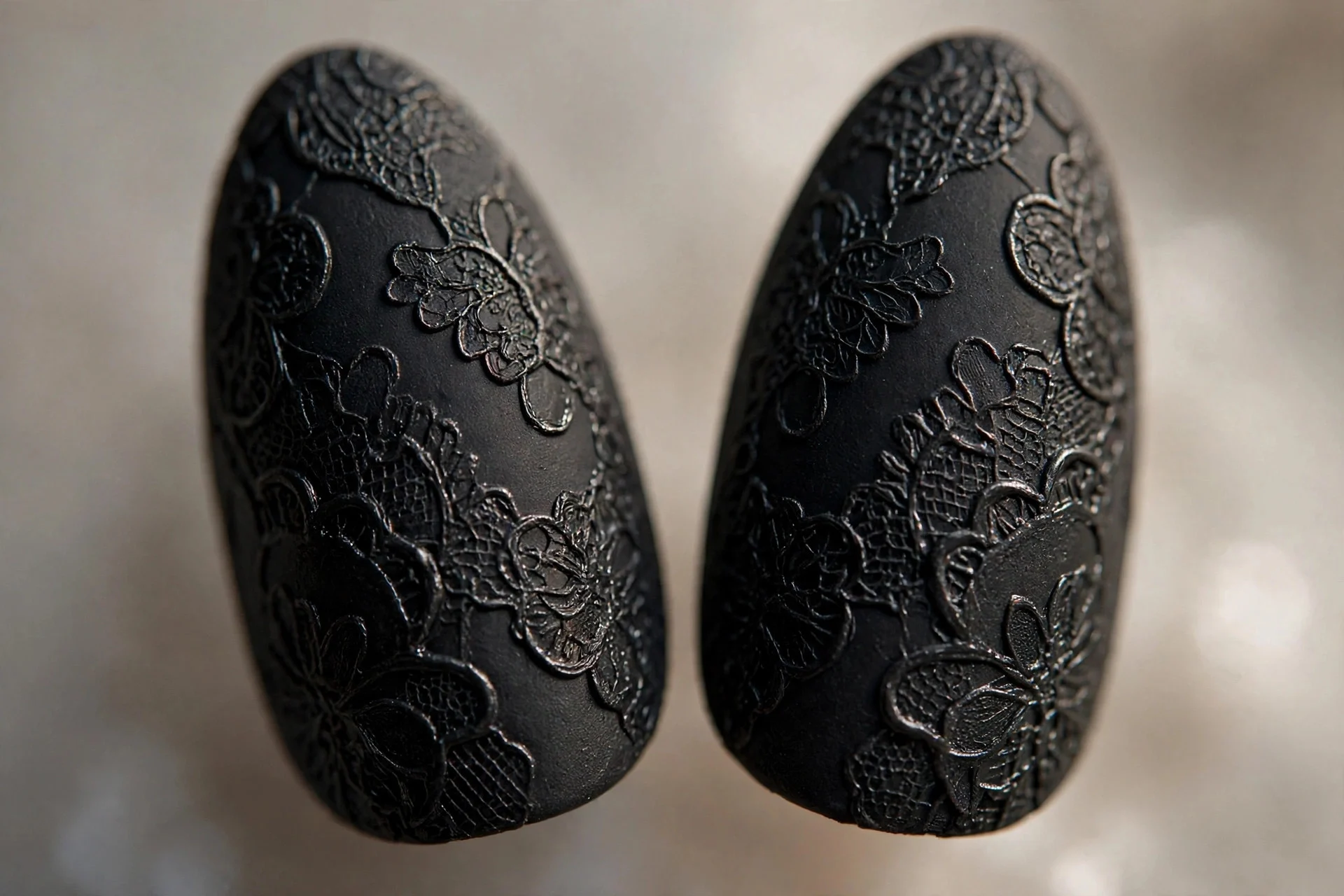 Almond nails with matte lace visible only as shine contrast over glossy black, neutral background