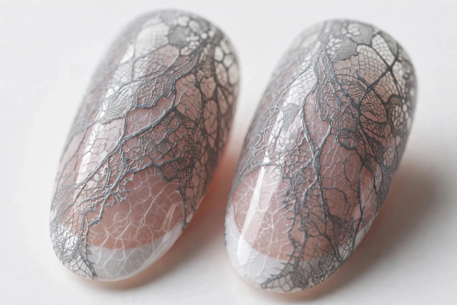 Almond French nails veiled under sheer gray lace stamping, glossy, white background