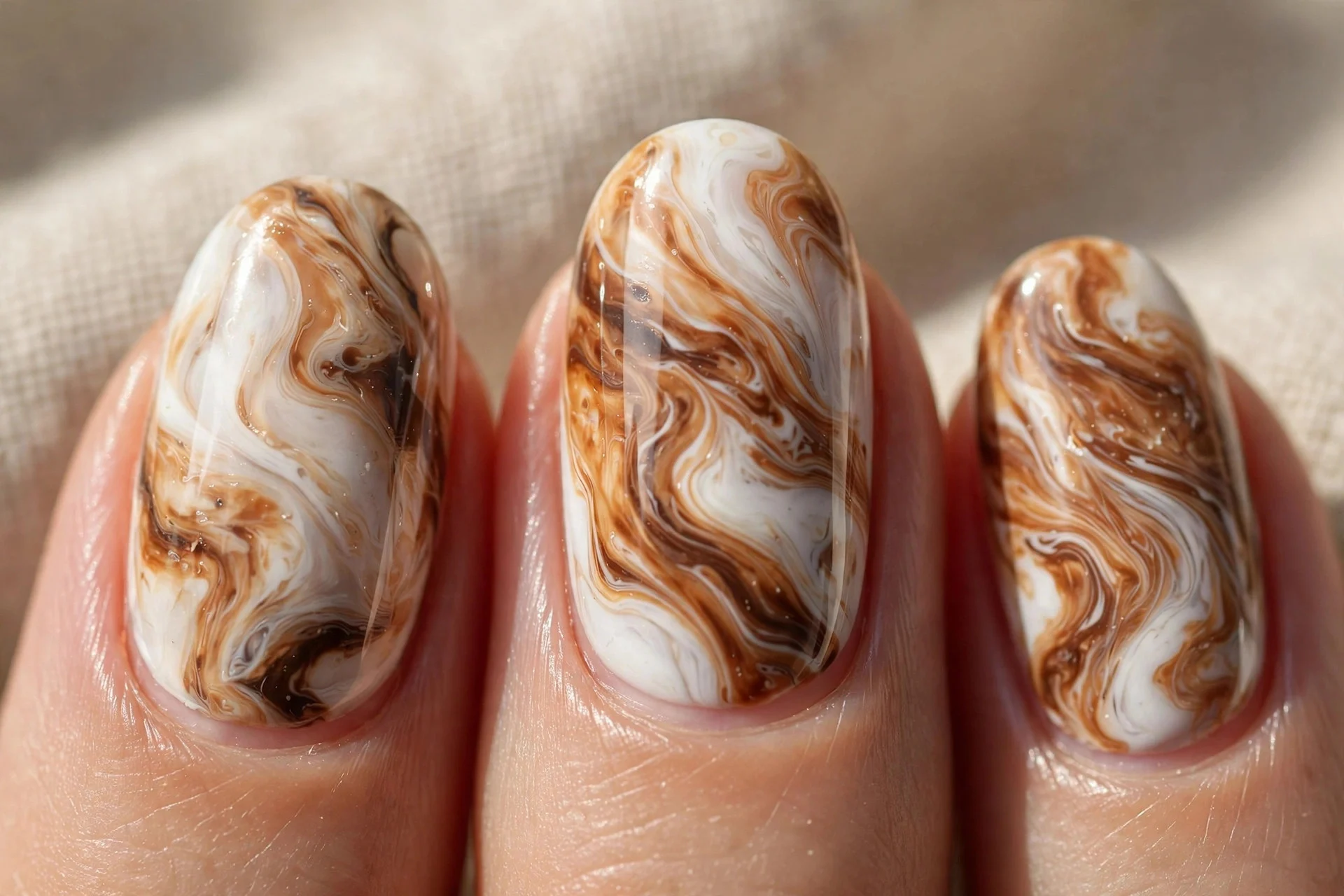 Marble-effect nails blending white, caramel, and brown tones.
