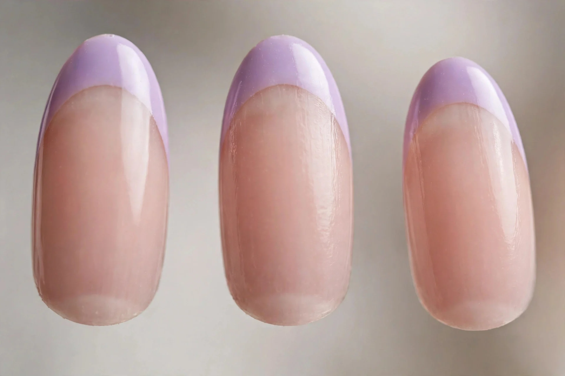Sheer nude base with lilac French tips, almond nails