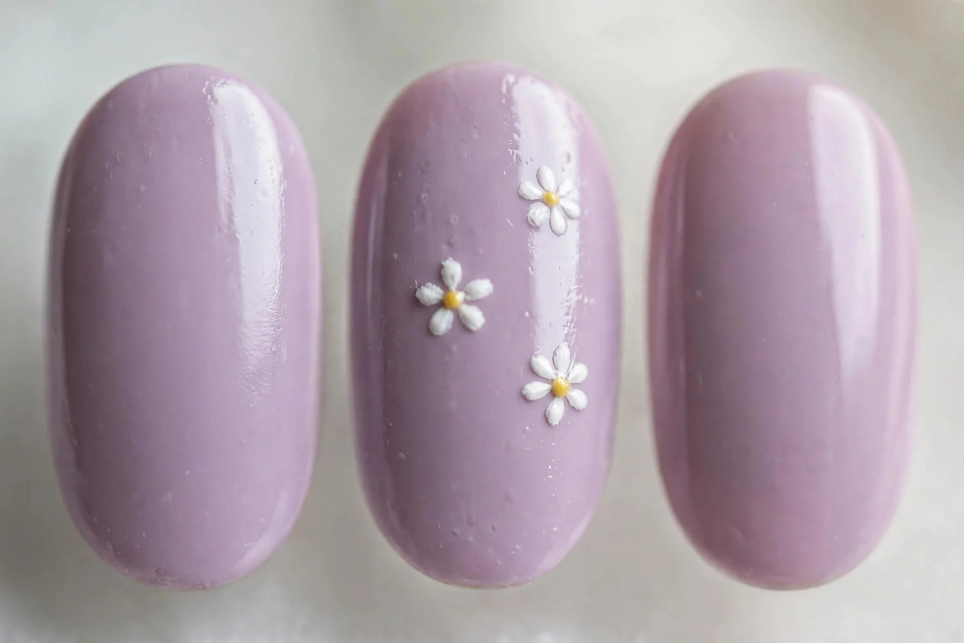 Lilac nails with tiny white daisy nail art on accent nails, oval