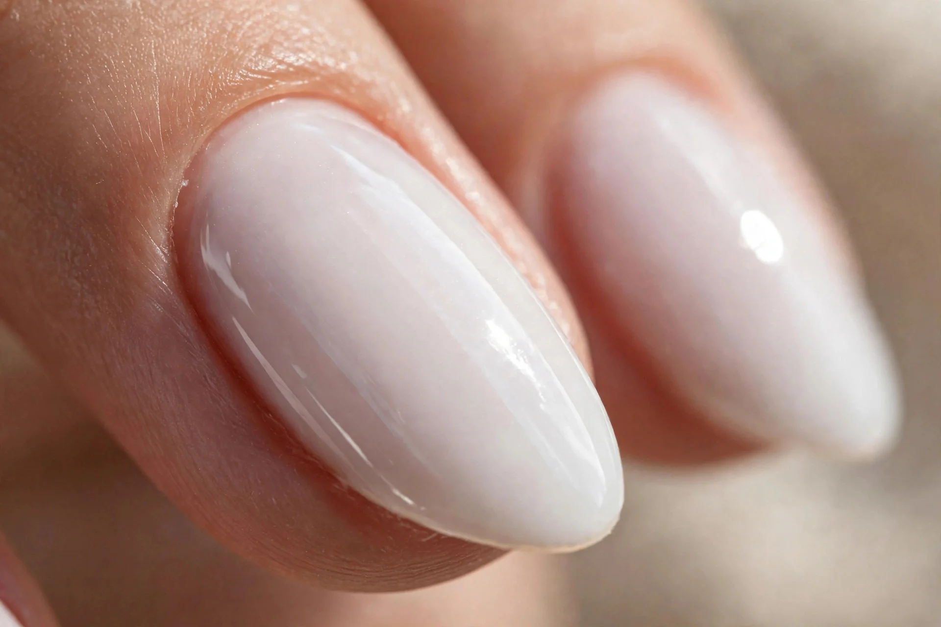 Extreme macro of an almond nail tip in milky white polish showing the sealed capped free edge, glossy finish, soft daylight, 