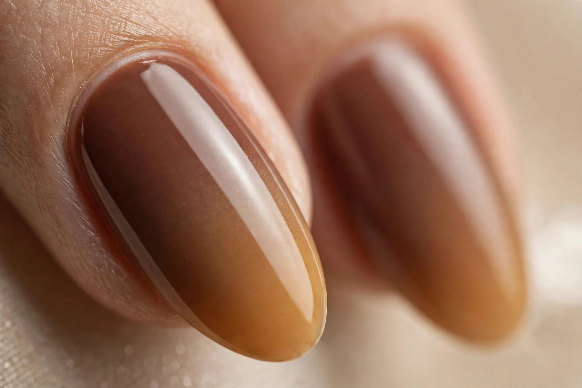 Almond nails with mocha-to-caramel ombre gradient, glossy, beige background