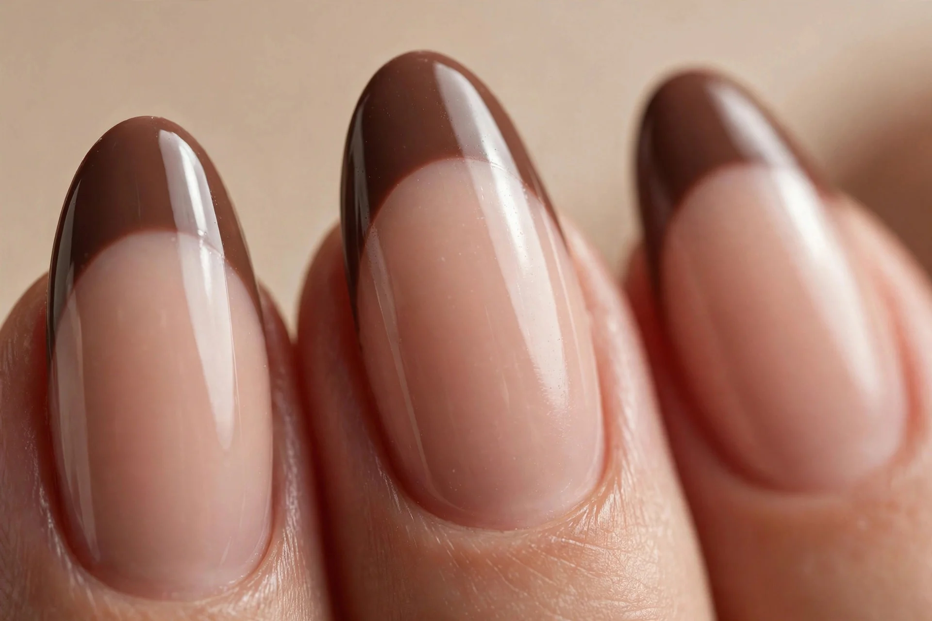 Almond nails with a nude base and deep mocha French tips, glossy, beige background