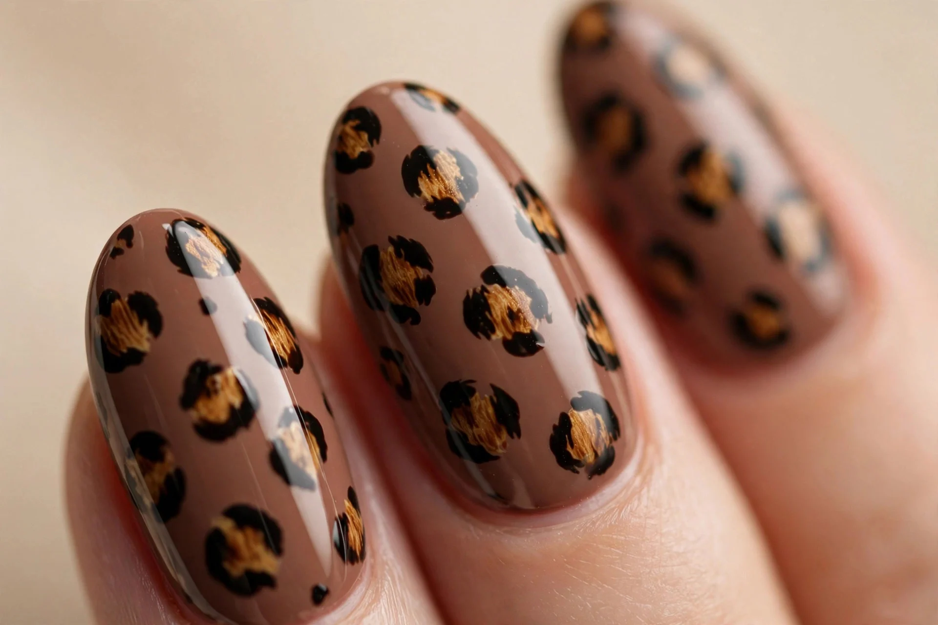 Almond nails with a mocha base and hand-painted leopard spots, glossy, beige background