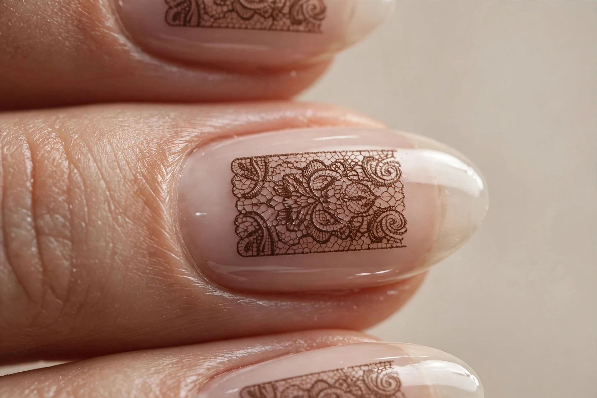 Almond nails with mocha lace stamping in a centered panel over bare nail, glossy, neutral background