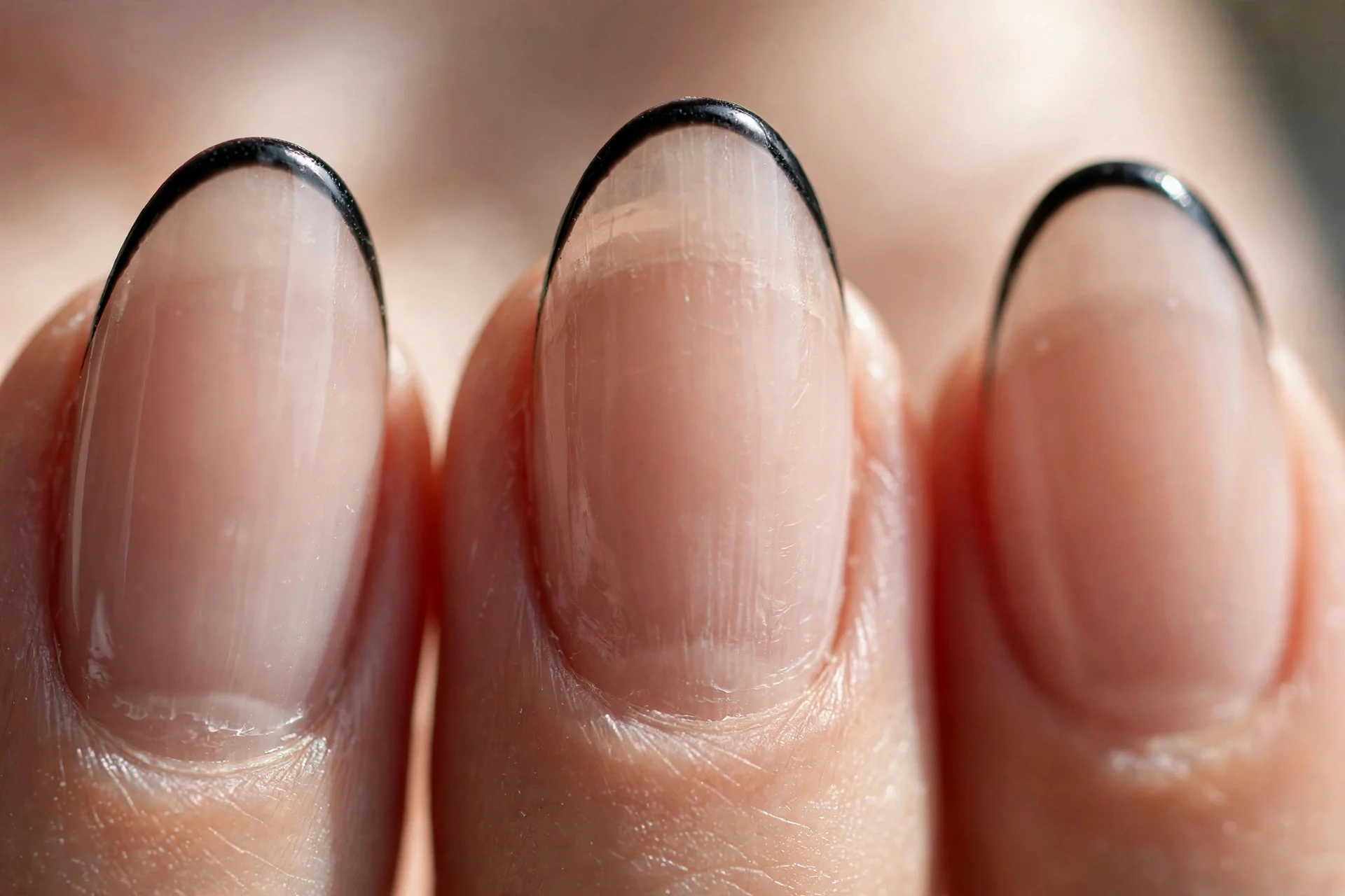 almond nails with sheer nude base and ultra-thin black French tips