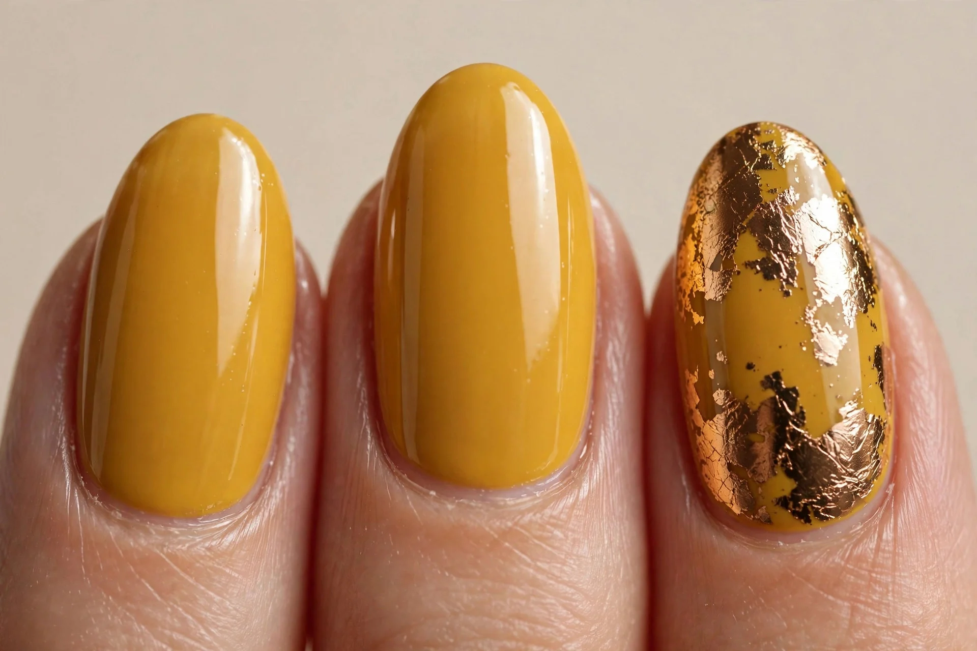 golden mustard glossy polish on medium almond nails, one ring finger with bronze chrome foil accent