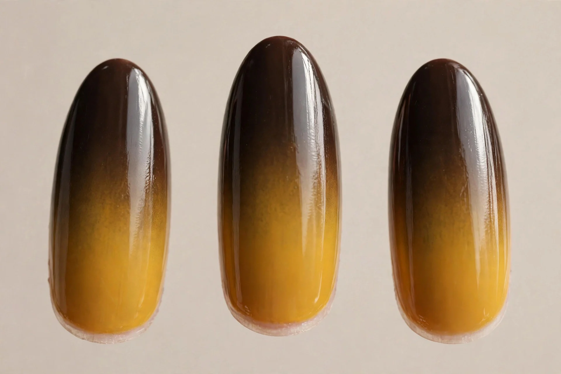 dark espresso at cuticle blending into golden mustard at tips, medium almond nails, glossy ombre