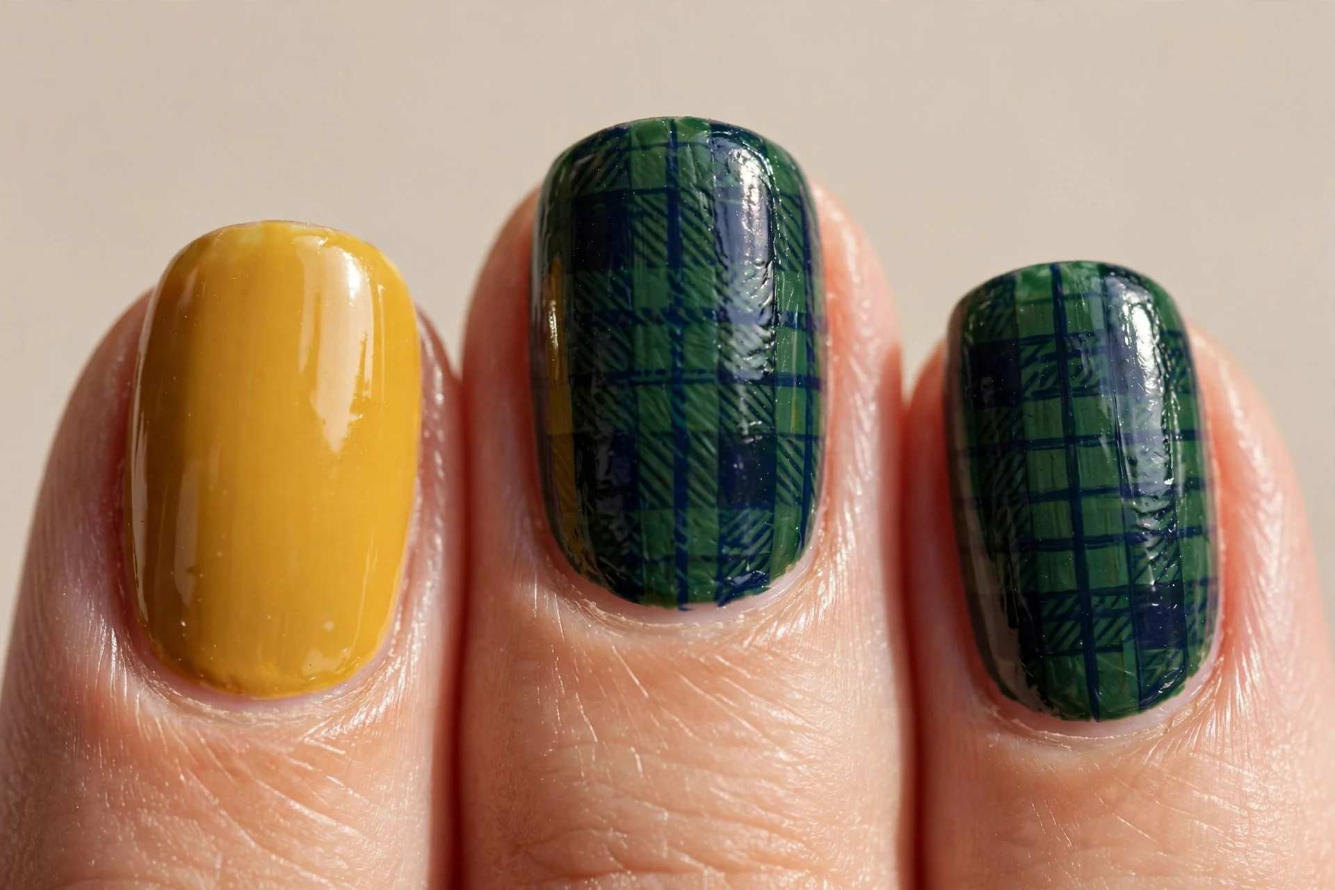golden mustard glossy base, two accent nails with hand-painted dark green and navy tartan checks