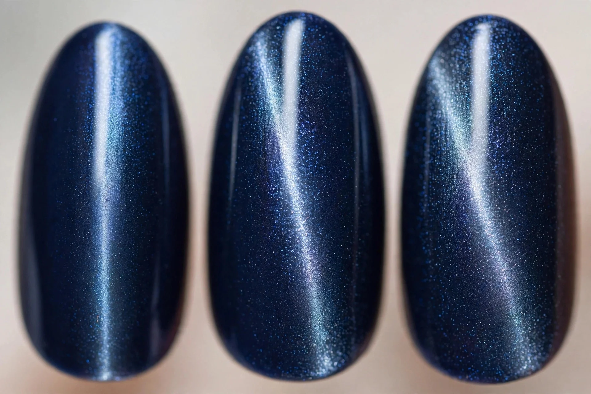 Navy magnetic cat-eye nails with silver-blue centre line, almond