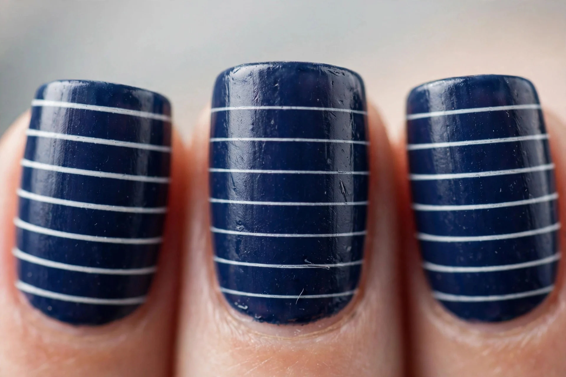 Navy nails with thin white stripes, short square nails