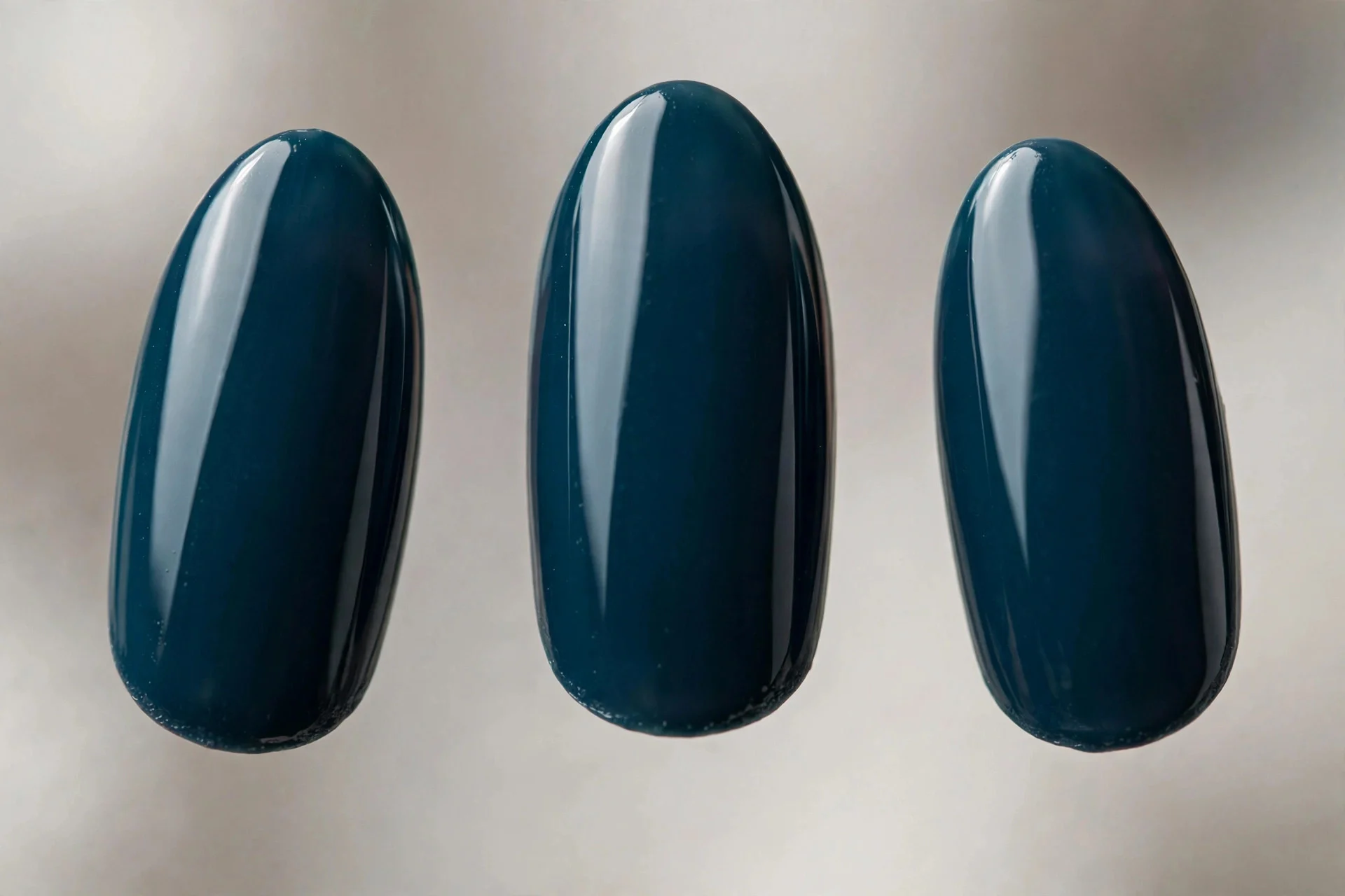 Deep petrol navy-teal polish, medium almond nails, glossy