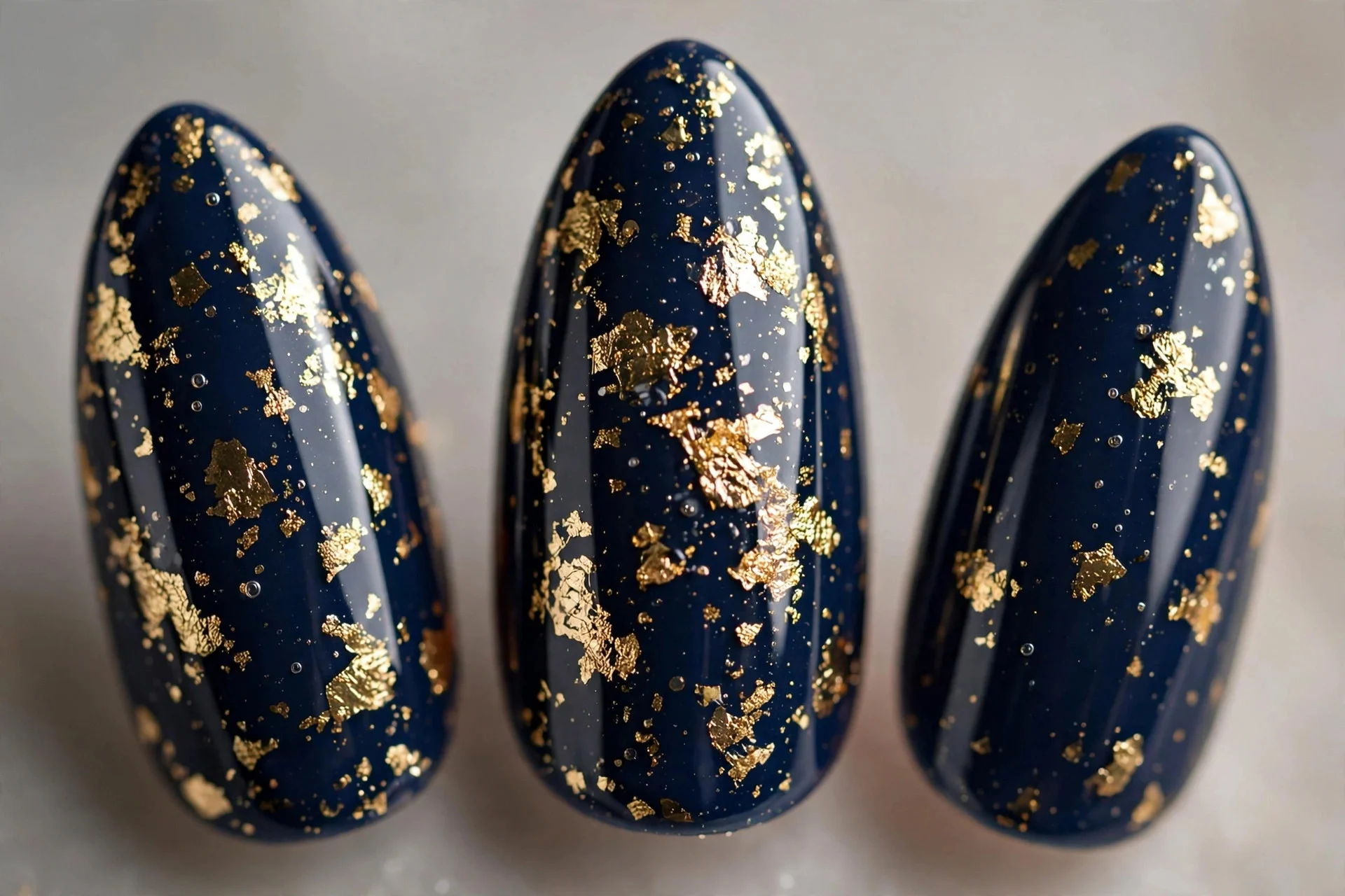 Navy nails with gold foil flakes, medium almond nails, glossy