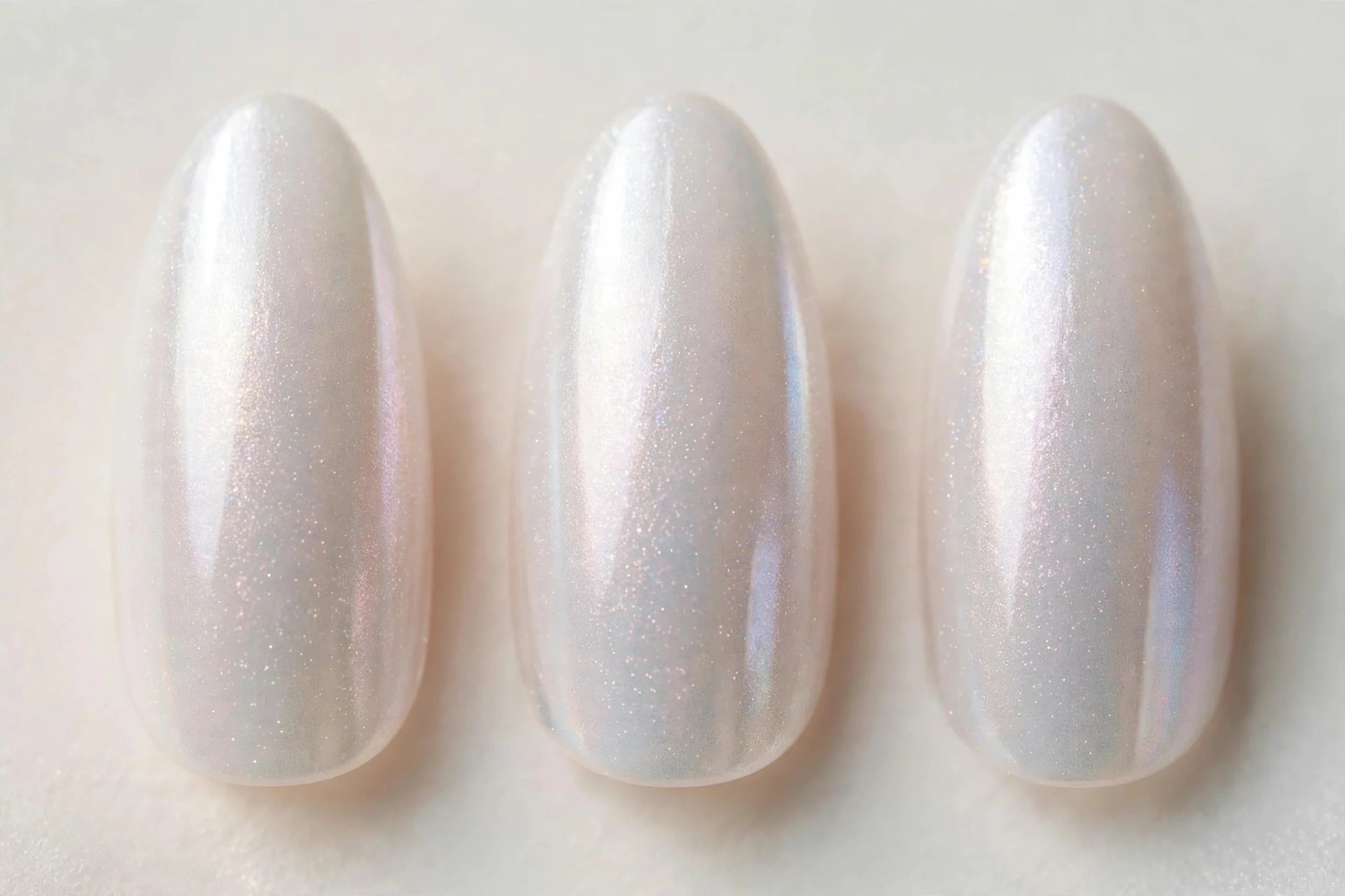 Long almond nails in pearl white iridescent shimmer, pale background