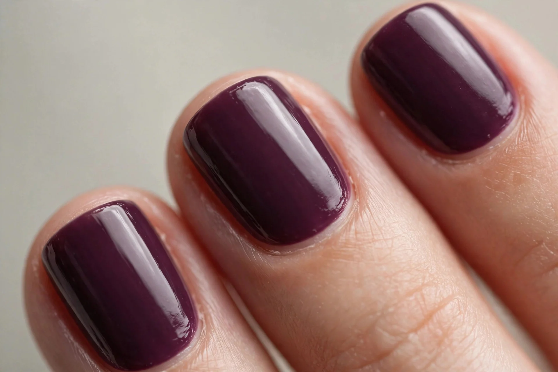Short squoval nails in deep plum gel, neutral background