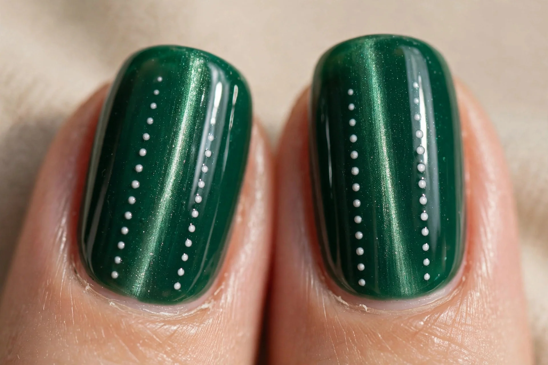 Extreme macro of two fingernails in emerald green cat-eye gel with a crisp vertical shimmer line, two neat vertical rows of t