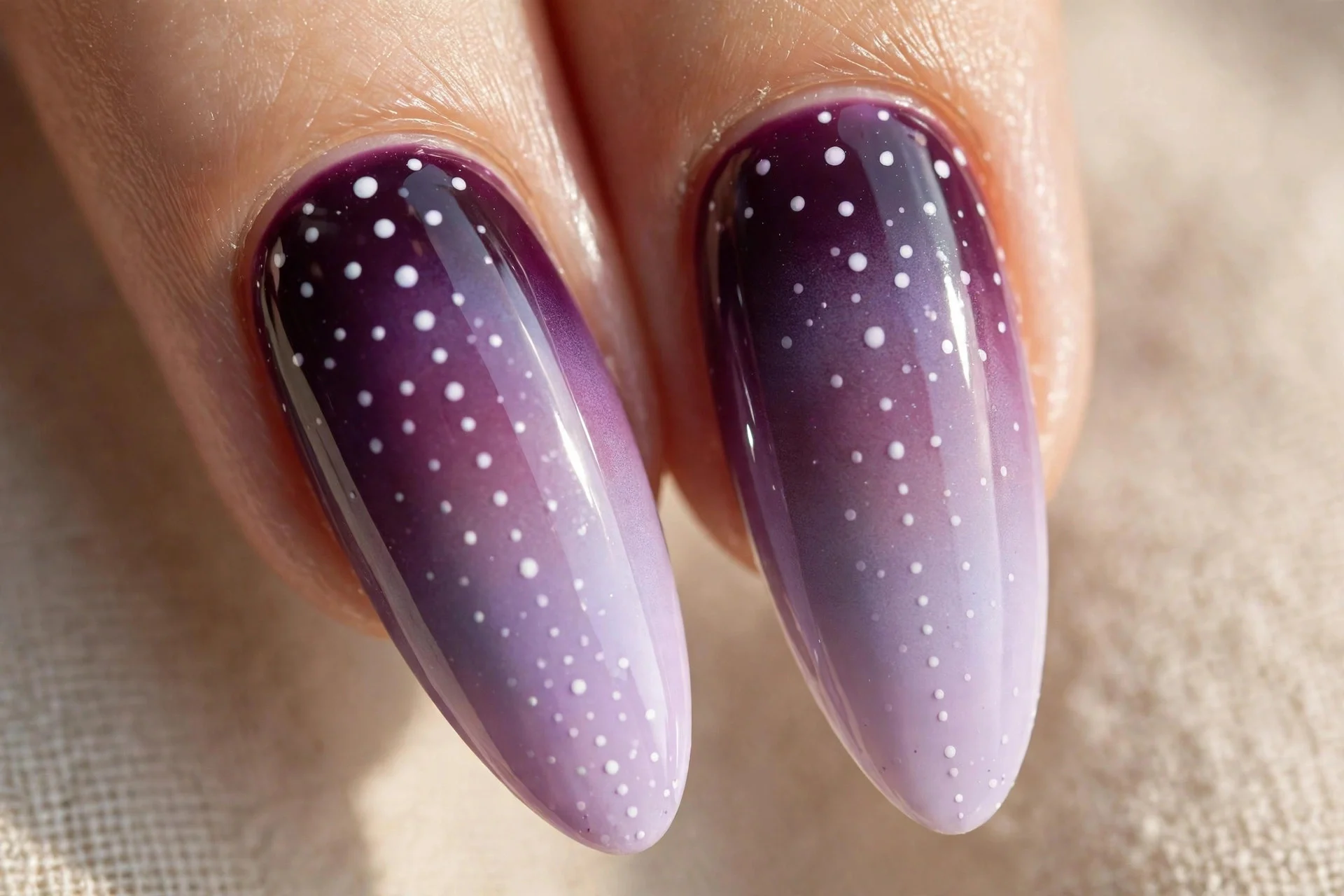 Extreme macro of two long fingernails with sponge-blended cat-eye ombré from deep plum at the cuticle to pale lilac at the ti