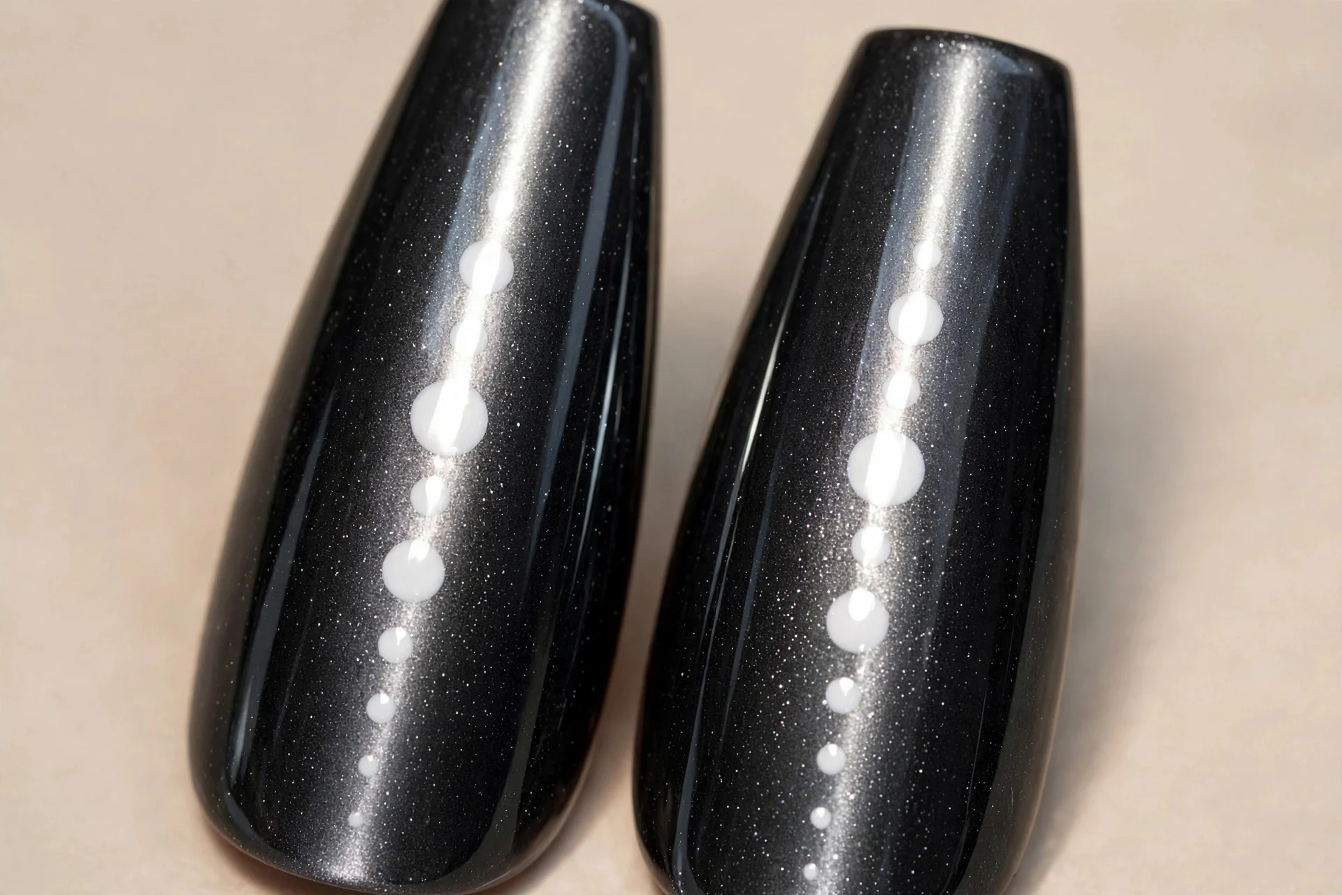 Extreme macro of two coffin fingernails in charcoal cat-eye gel with a dramatic vertical light band, alternating large and sm