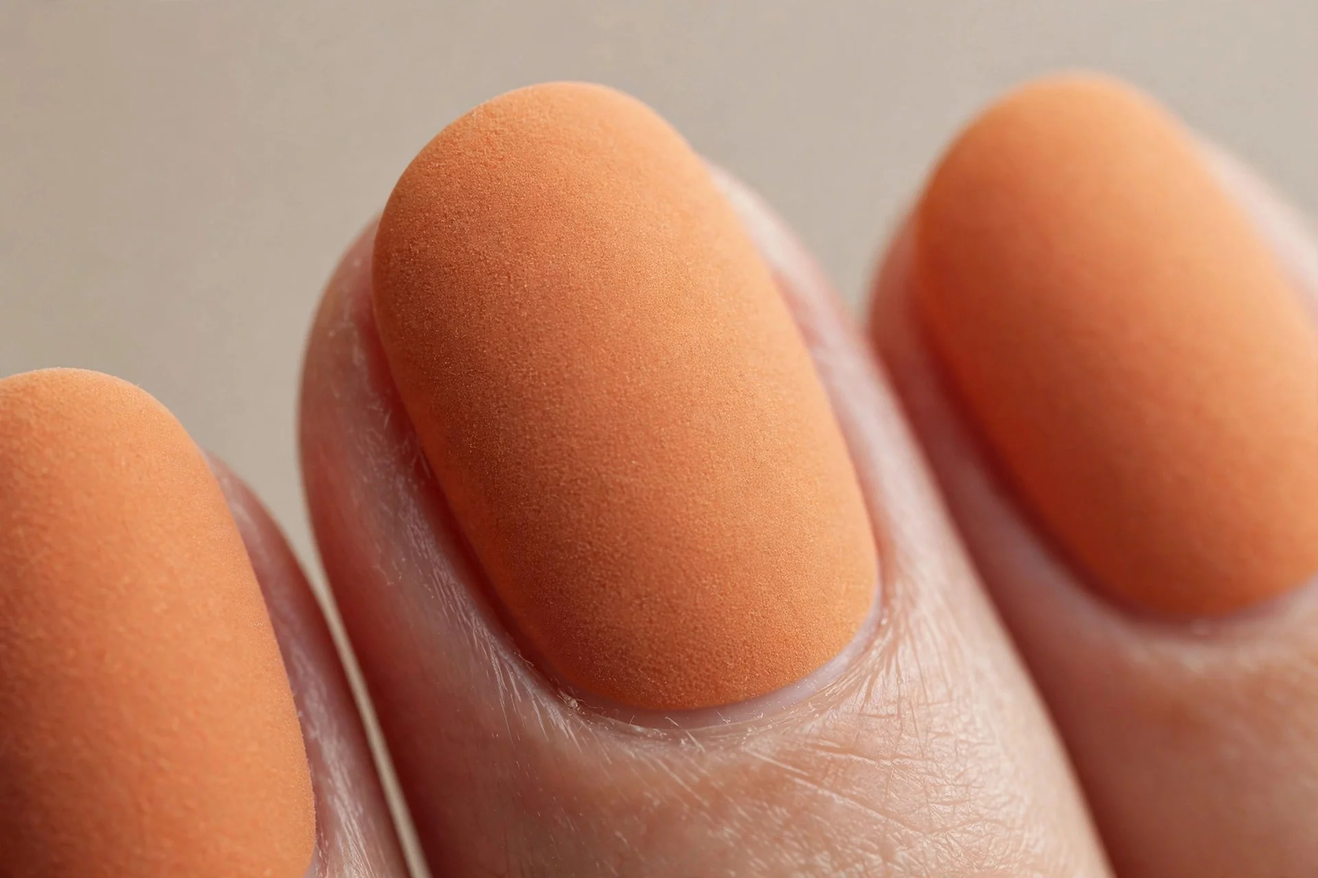 Short oval nails in matte pumpkin creme, suede-like finish, neutral background