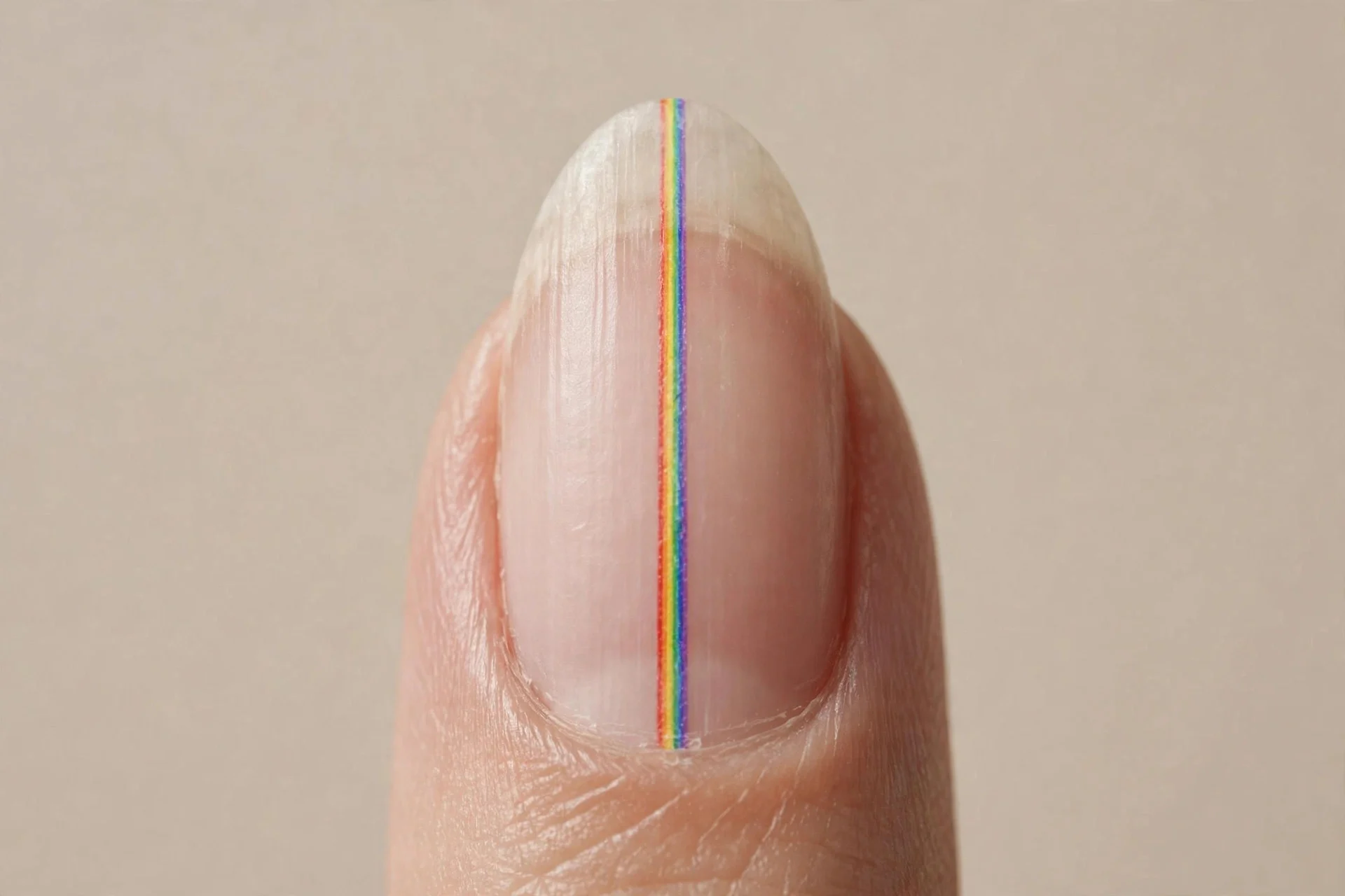 one almond fingernail, bare natural nail with a single thin rainbow stripe down the centre