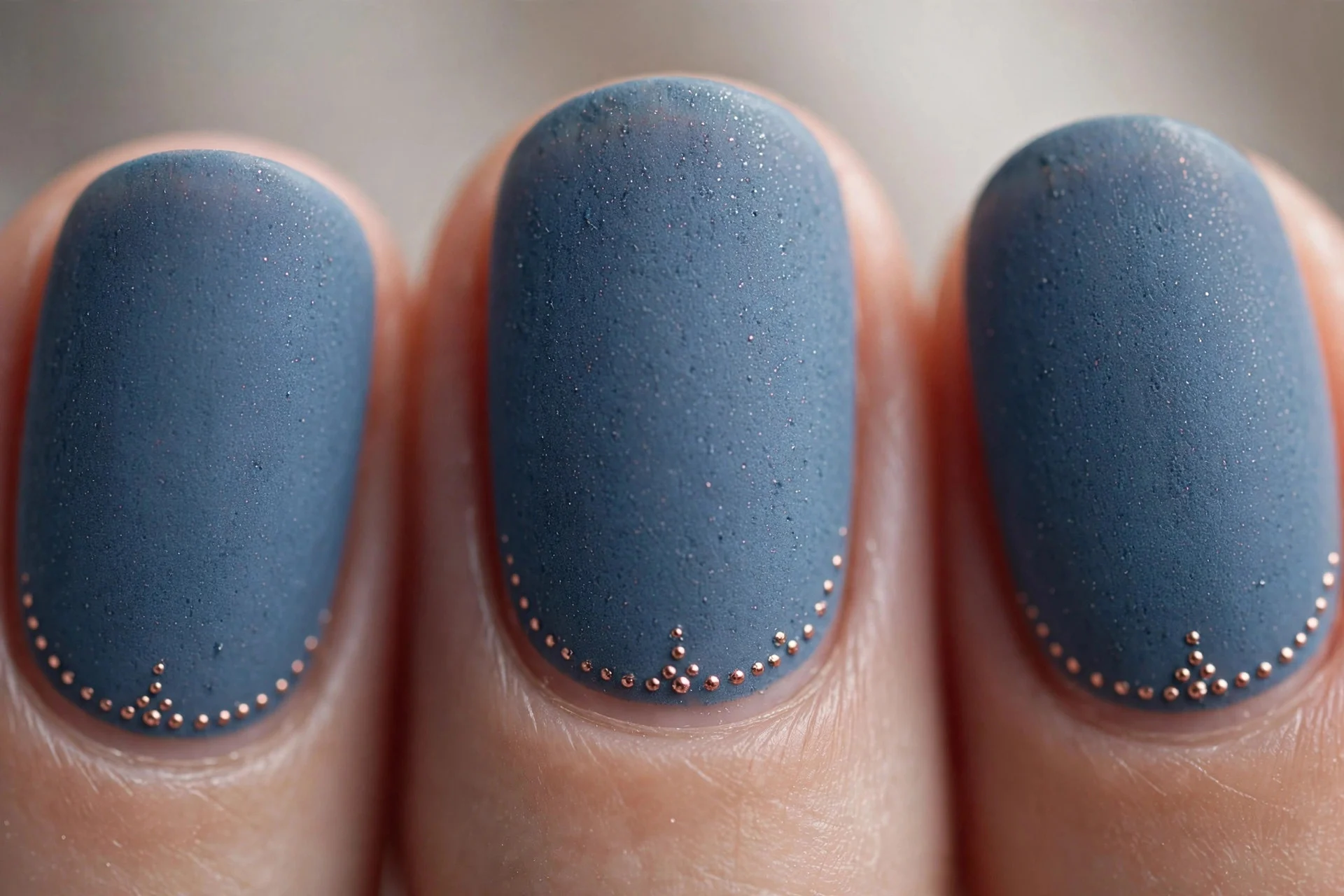 Dusty denim blue nails with tiny rose gold cuticle dots, short oval