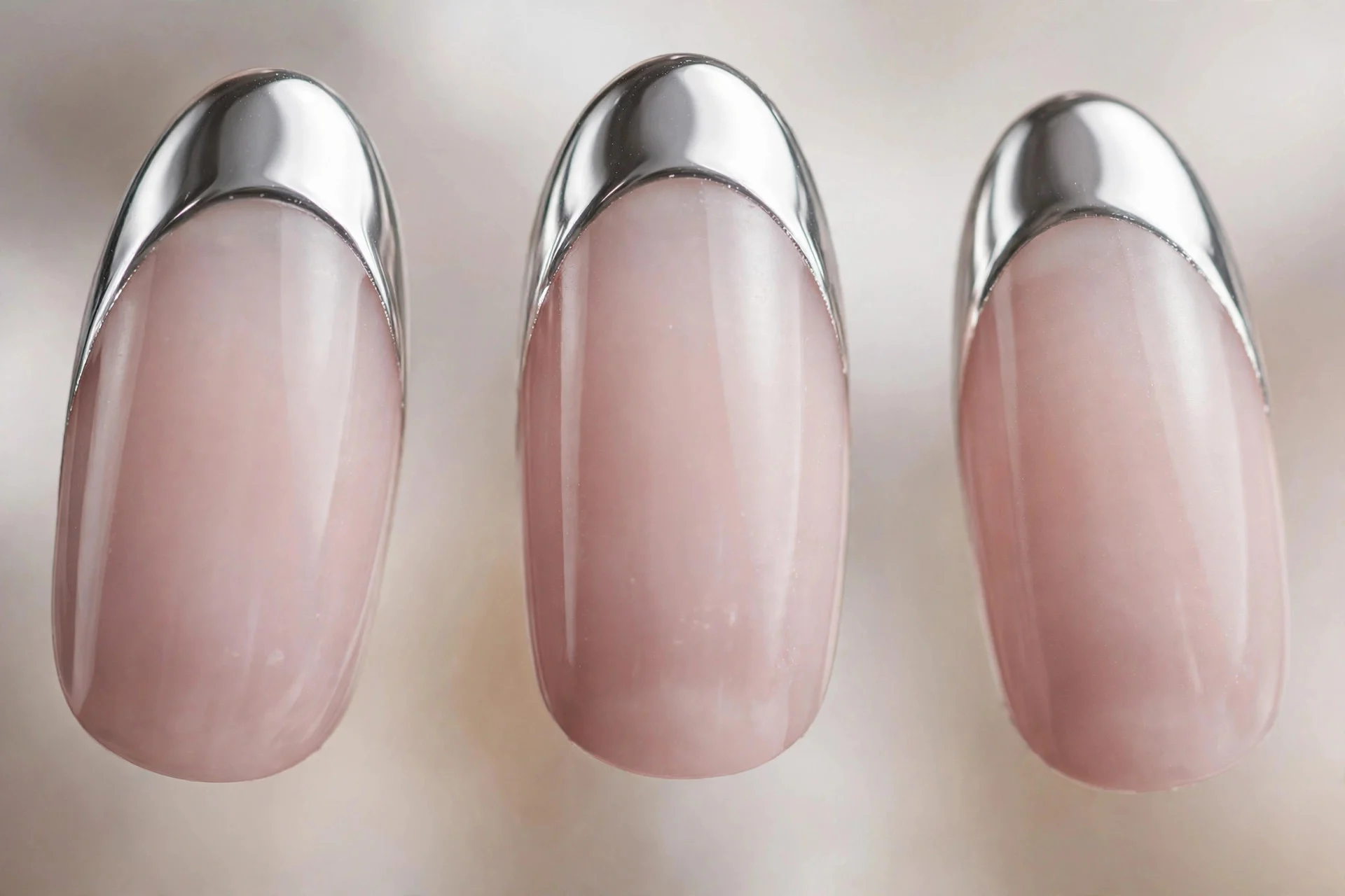 Sheer milky nails with liquid silver chrome French tips, almond