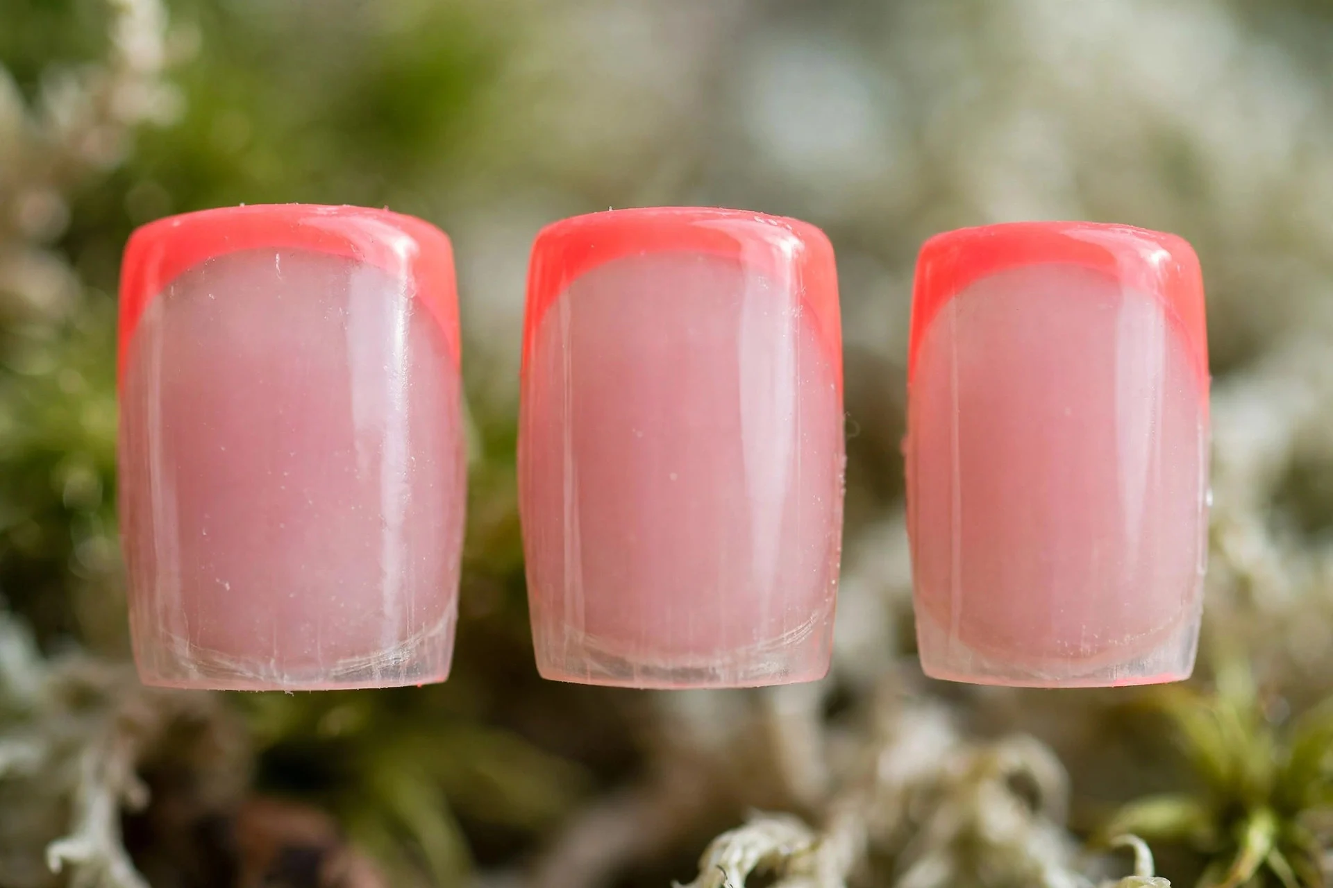 Sheer pink nails with neon coral French tips, square