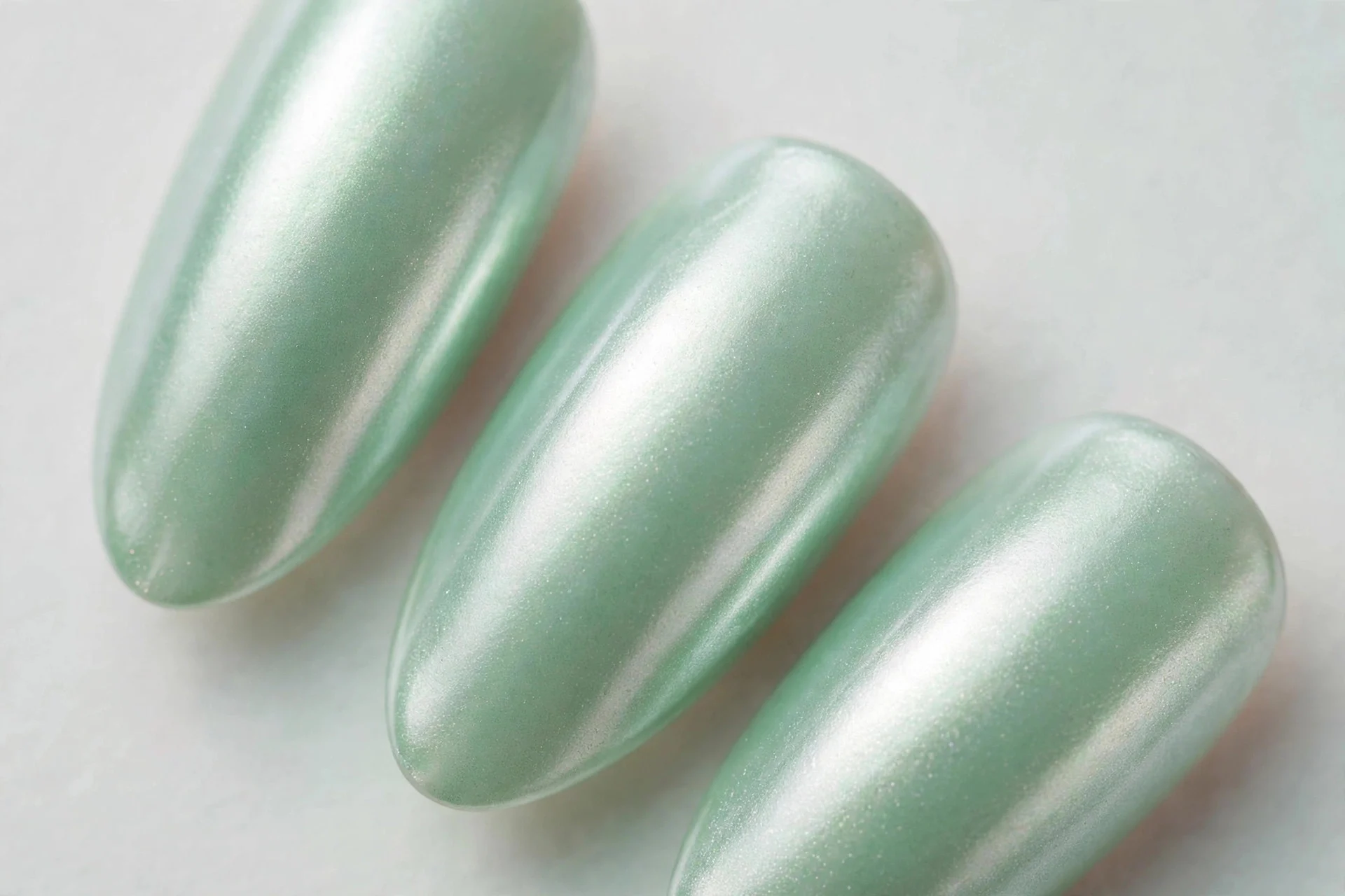 Almond nails with mint green under pearl chrome finish, luminous, light background