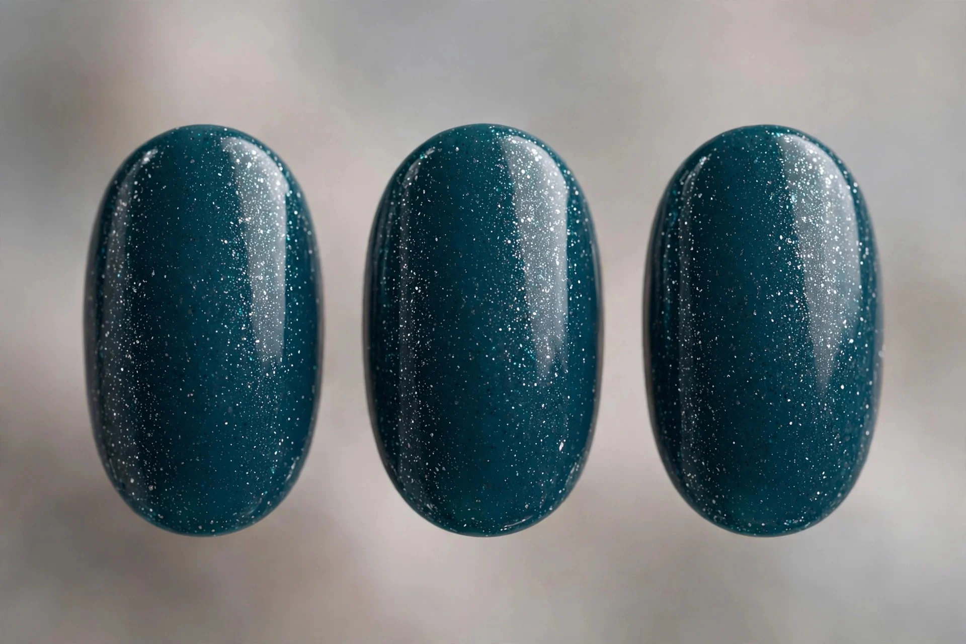 Deep teal polish with fine silver shimmer, oval nails