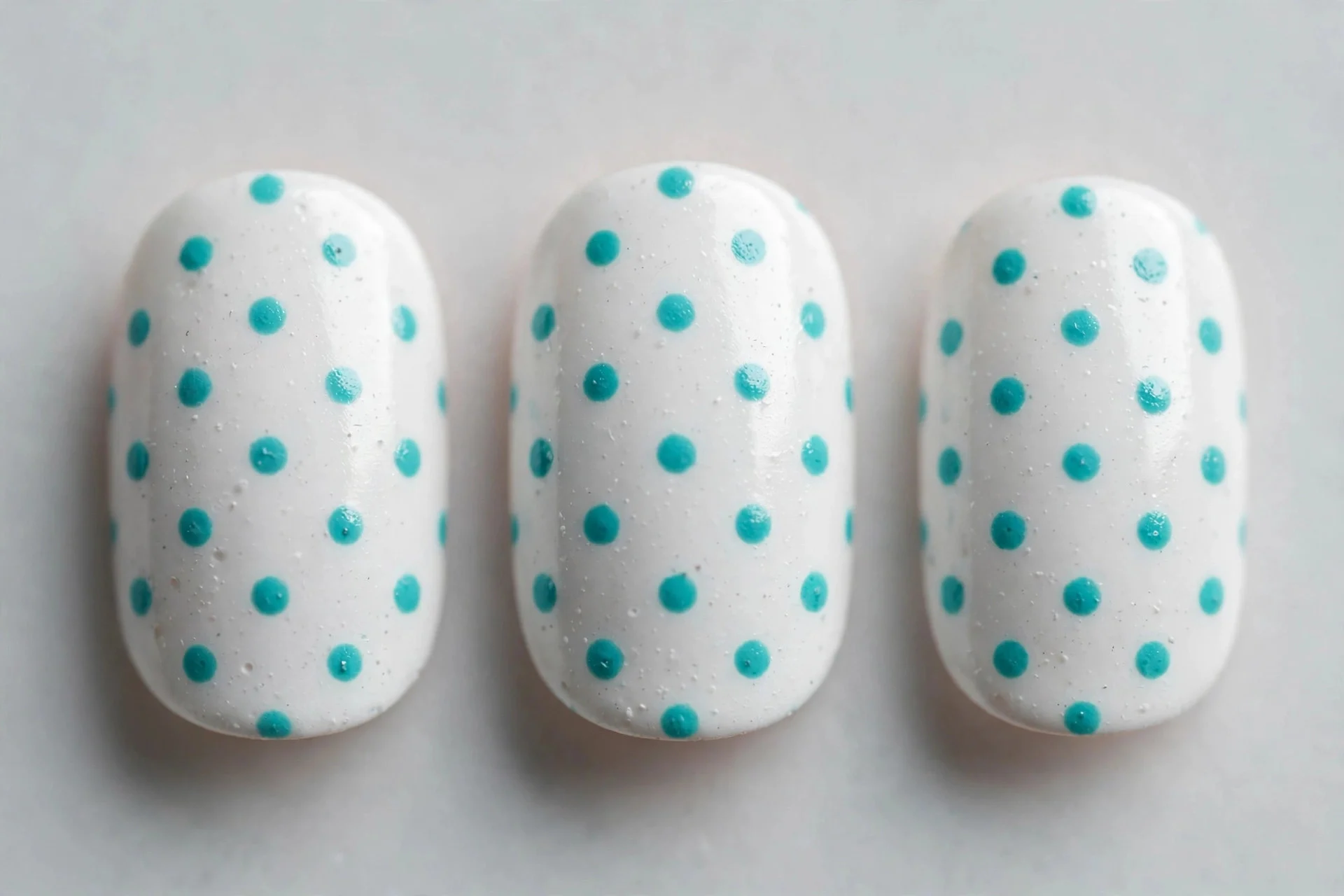 White nails with turquoise polka dots, short oval nails