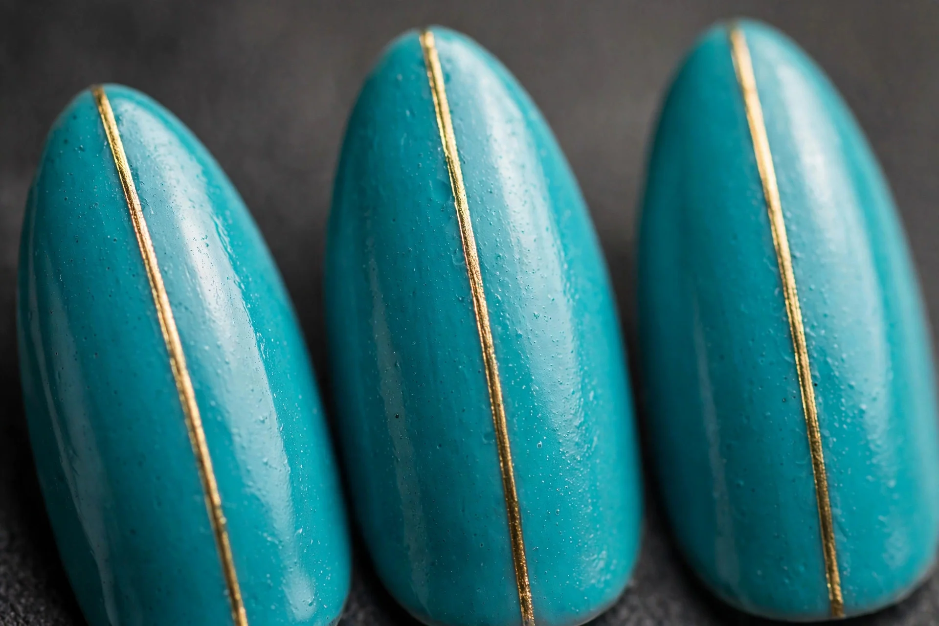 Turquoise nails with thin gold centre stripe, almond