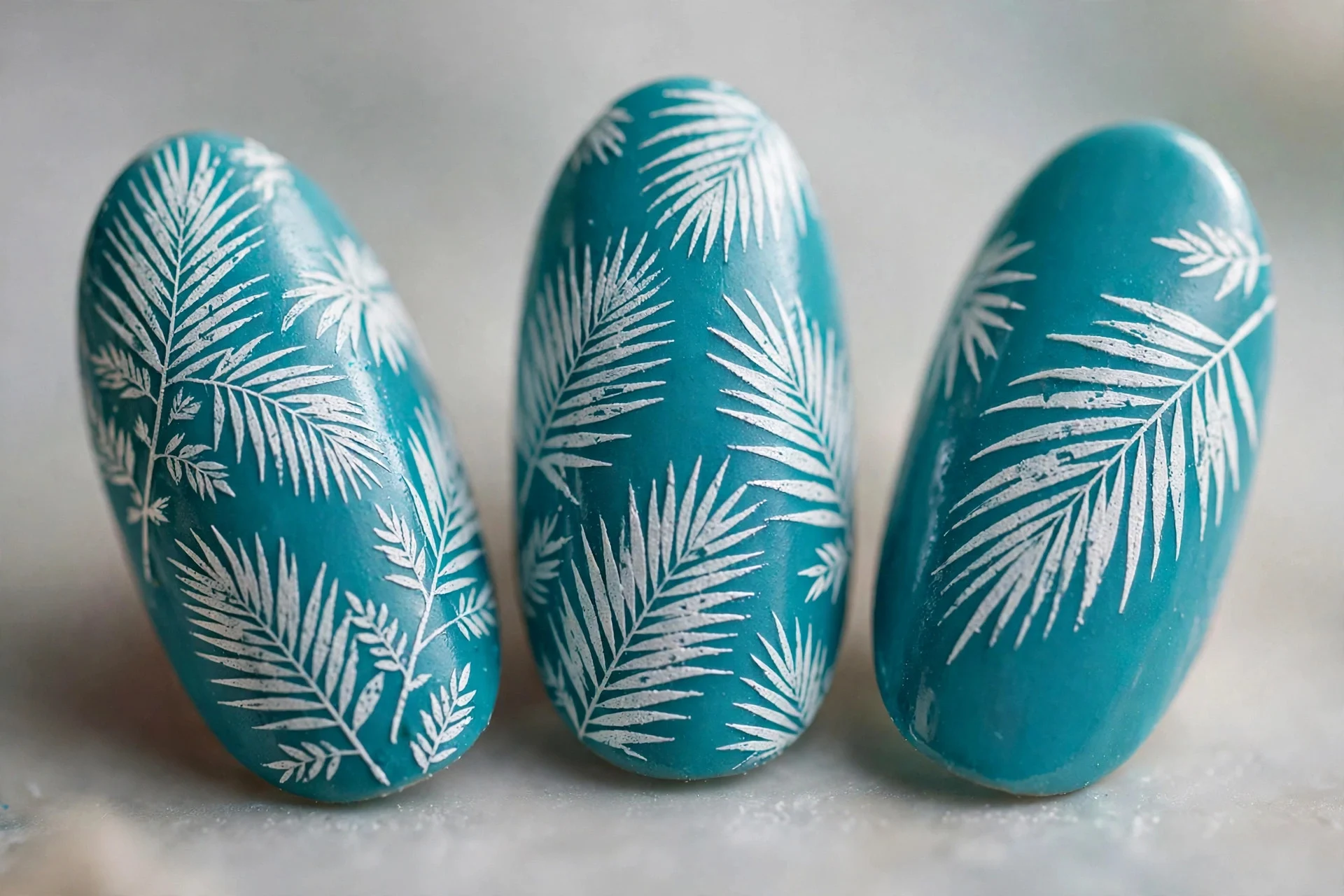 Turquoise nails with stamped white palm leaf designs, almond