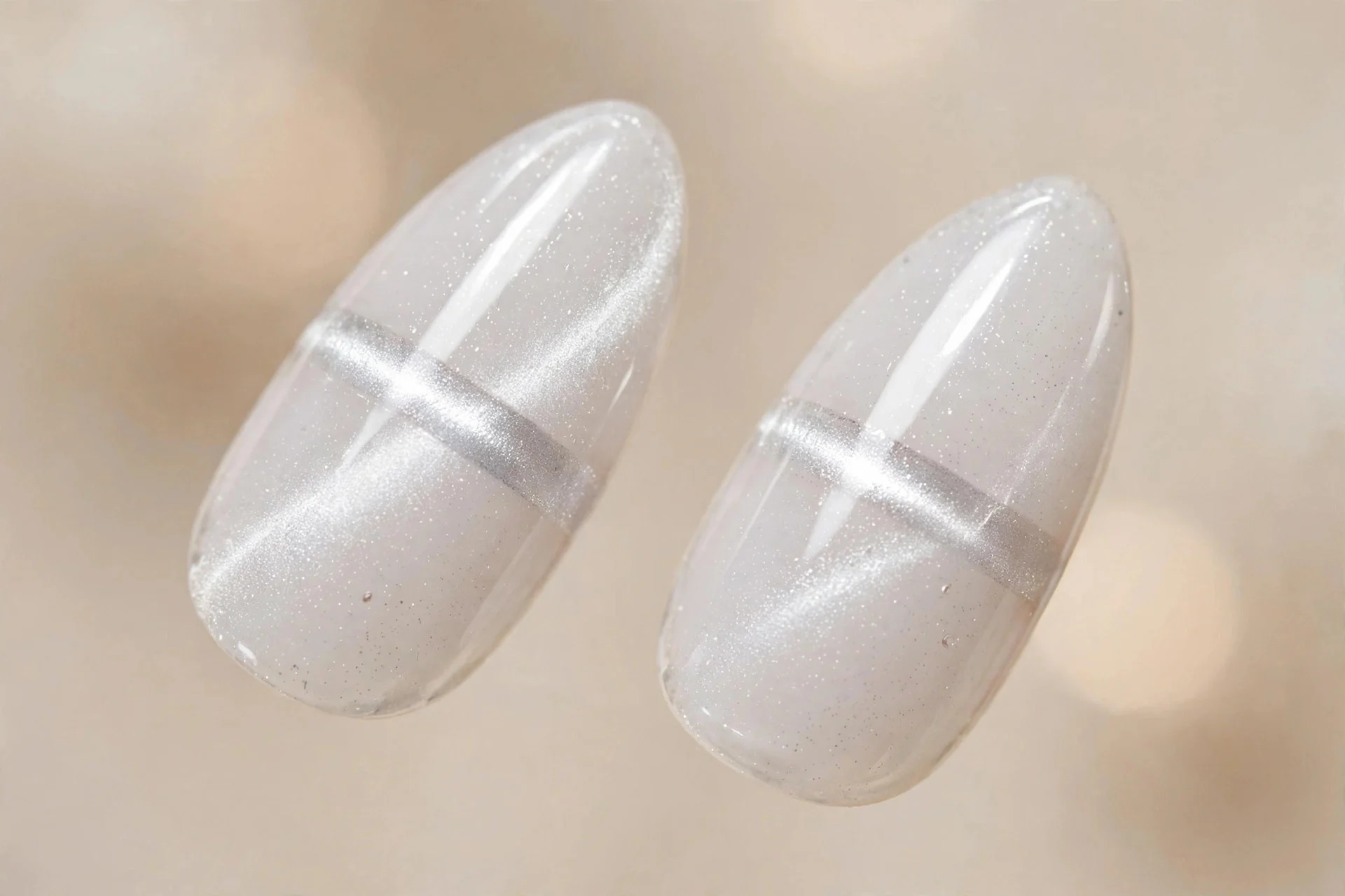 Extreme macro of two almond fingernails, sheer white cat-eye gel, silver light band, glossy, beige background