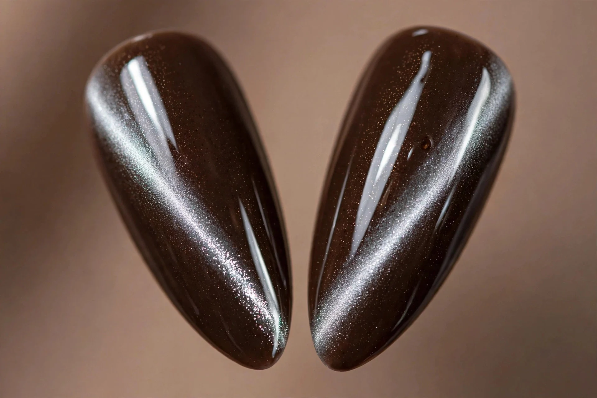 Extreme macro of two almond fingernails, espresso brown cat-eye gel, icy silver band, glossy, taupe background
