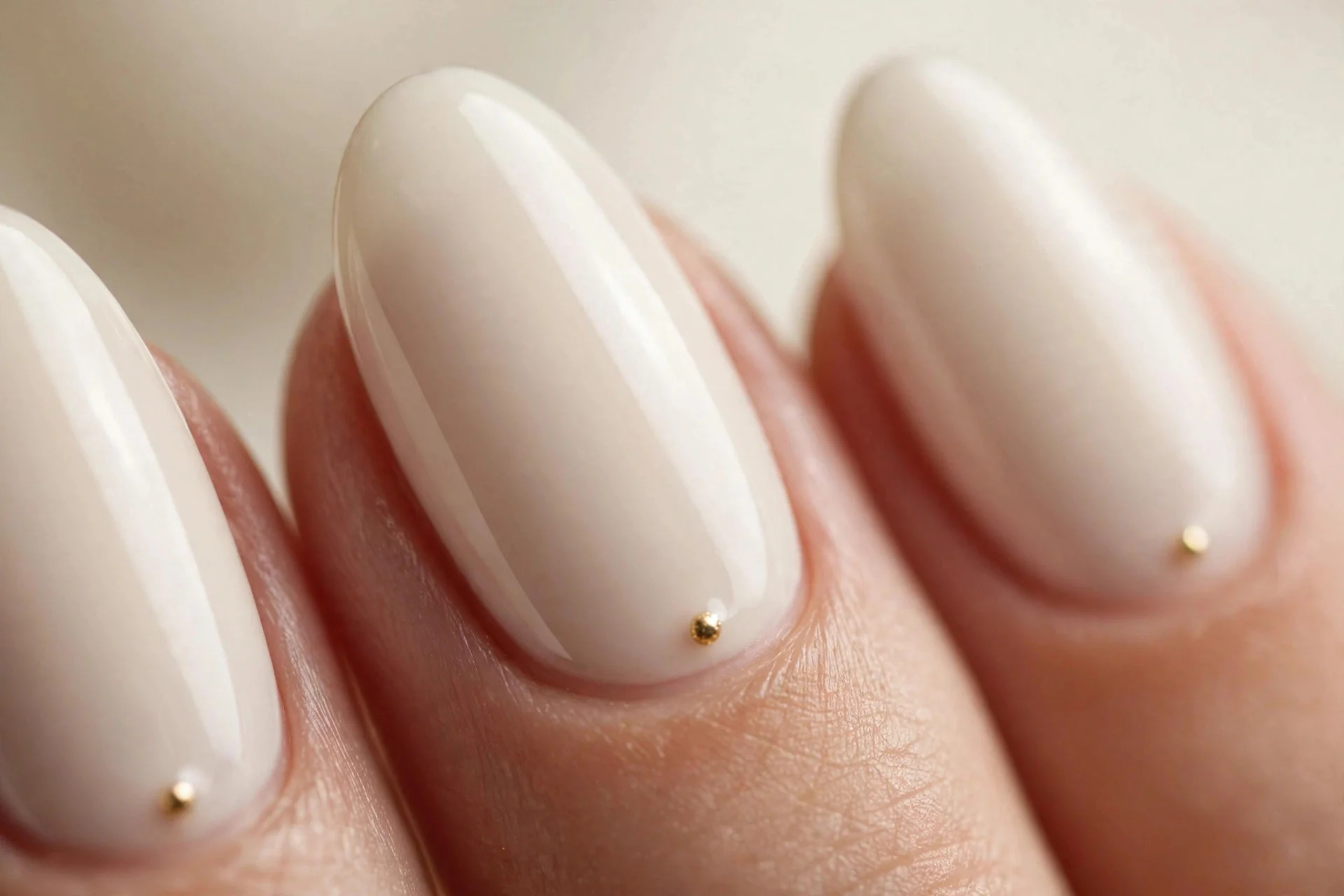 Almond nails in vanilla creme with one tiny gold dot at each cuticle, glossy, cream background