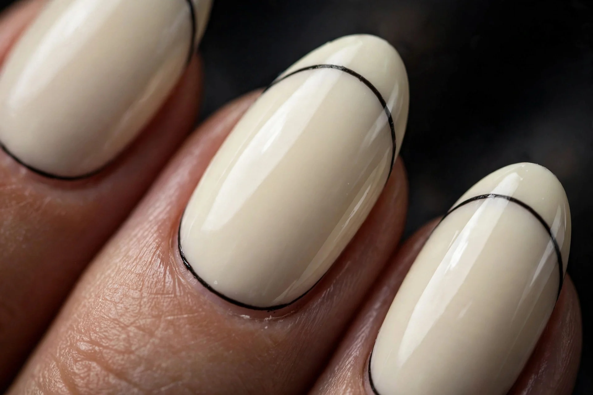 Almond nails in vanilla creme with thin black line along cuticle, graphic contrast, glossy, dark background
