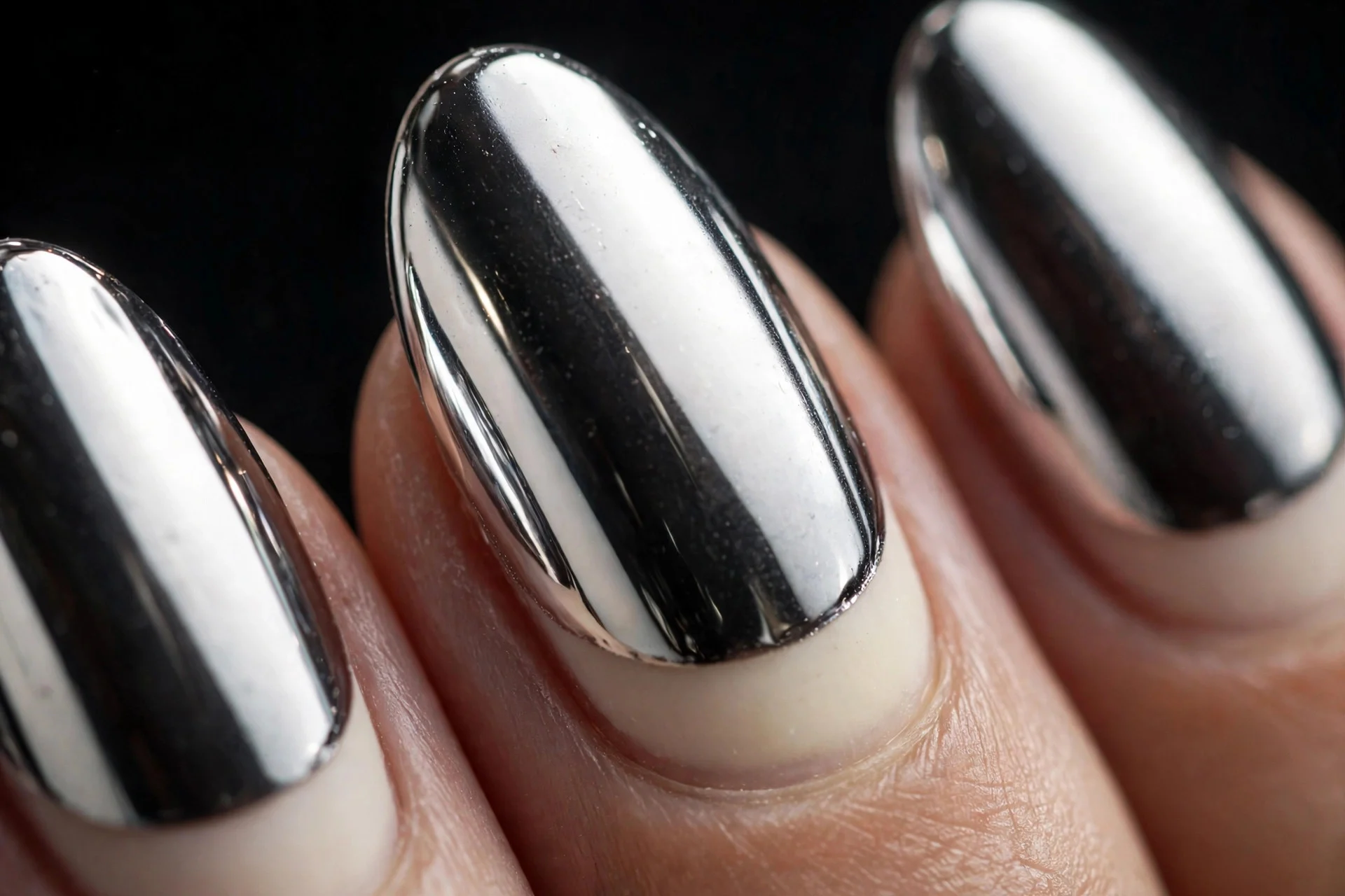 Almond nails with vanilla base and mirror chrome finish, reflective shine, dark background