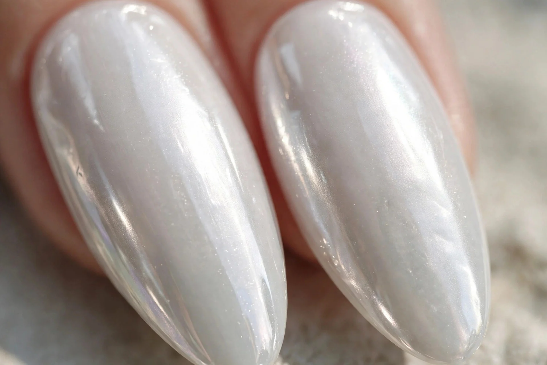 two almond fingernails in pearly white glaze with a luminous chrome glow