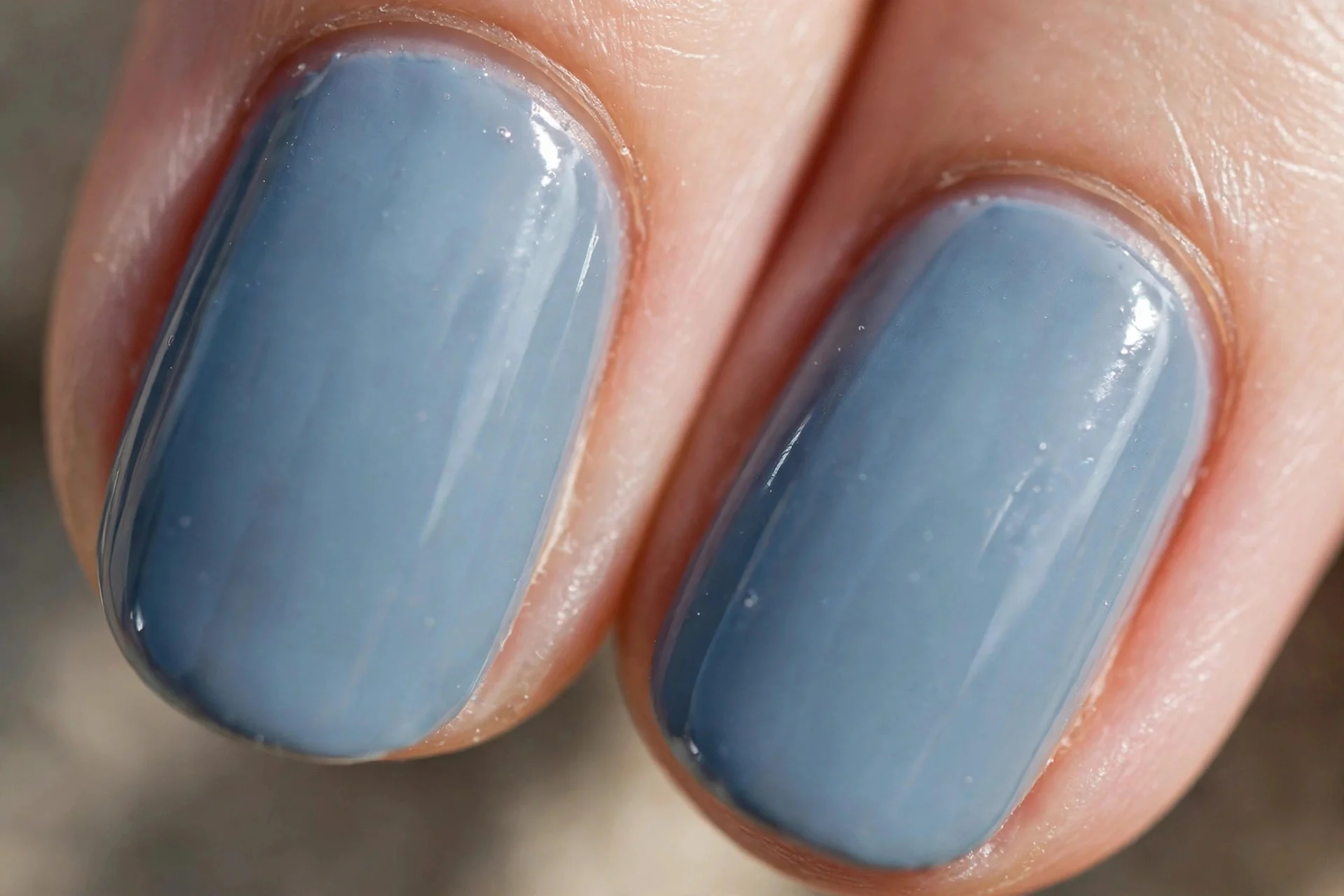 two oval fingernails in dusty powder blue creme with a glossy finish