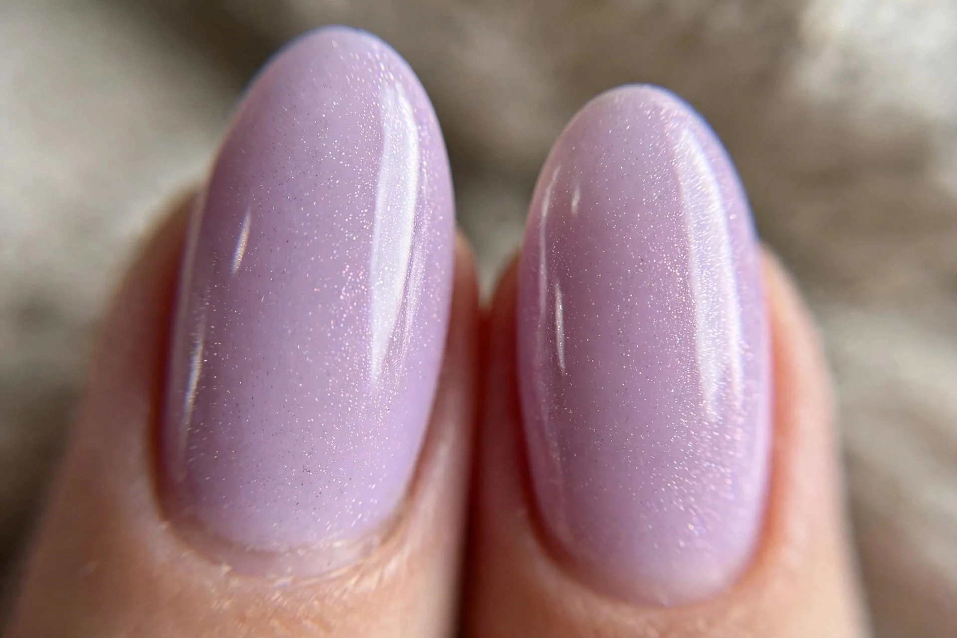 two almond fingernails in soft lilac with fine pearly shimmer