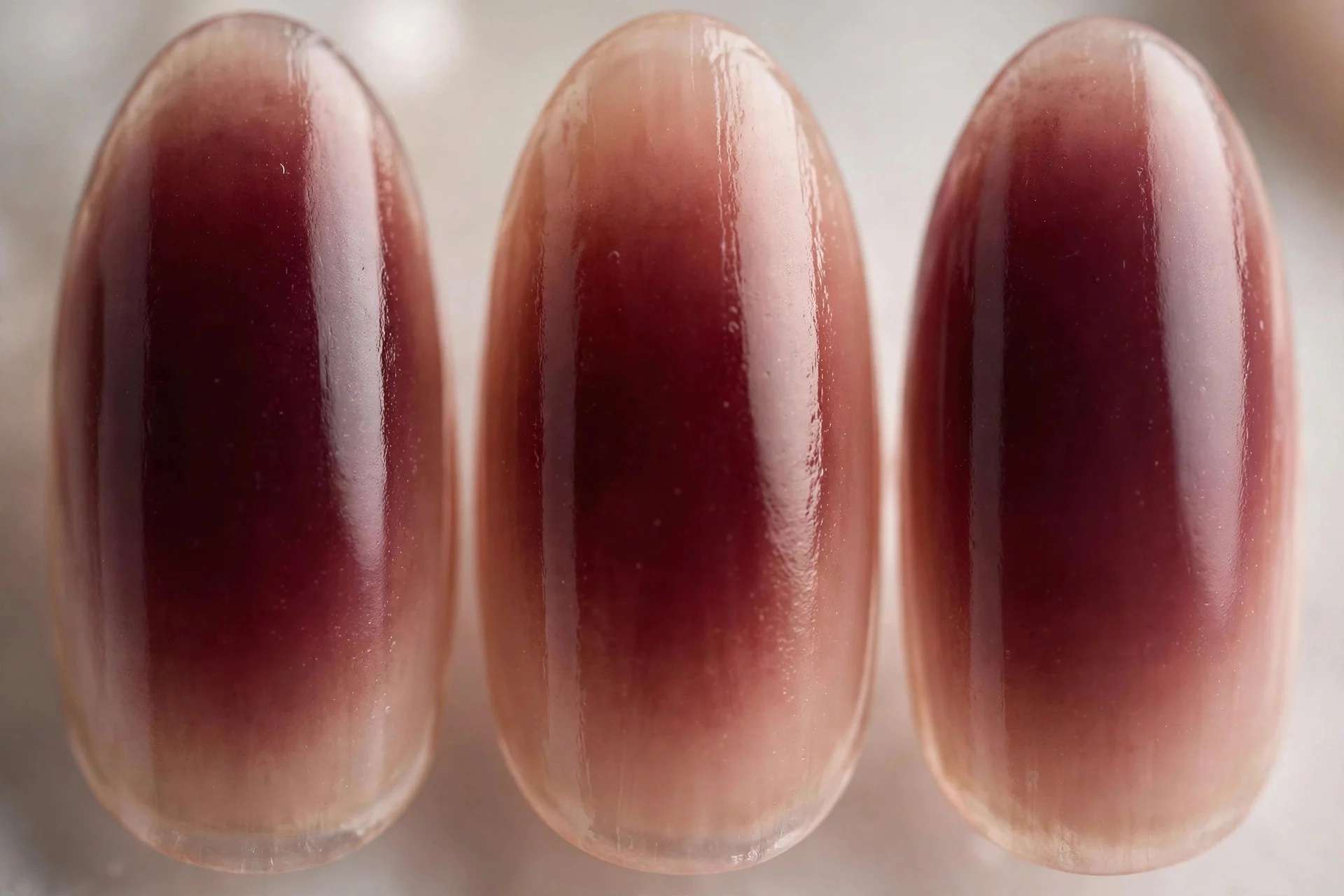 Deep wine aura fading to sheer nude edges, medium almond nails